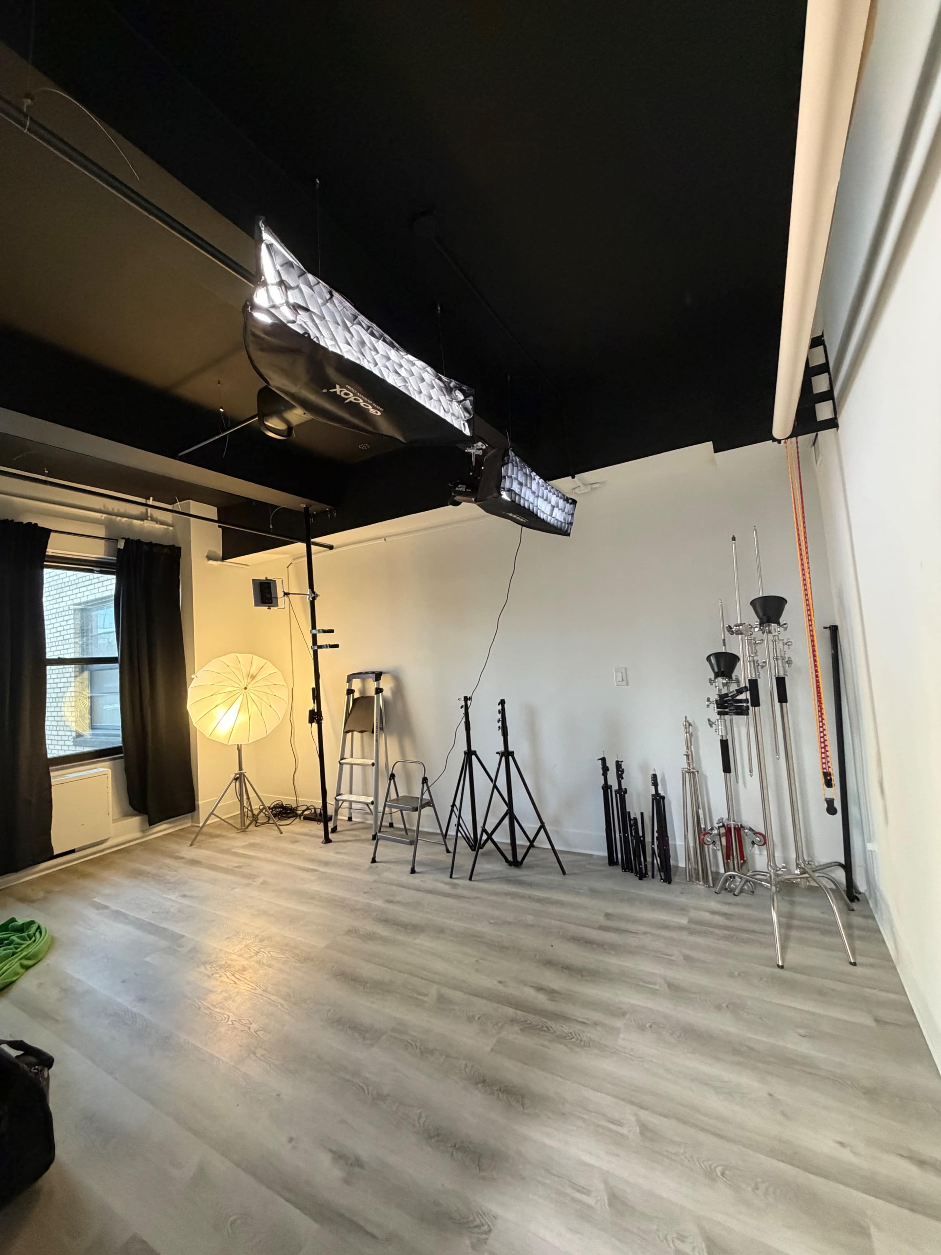 The image shows a photography studio with lighting equipment, backdrops, and tools neatly arranged in a well-lit space.