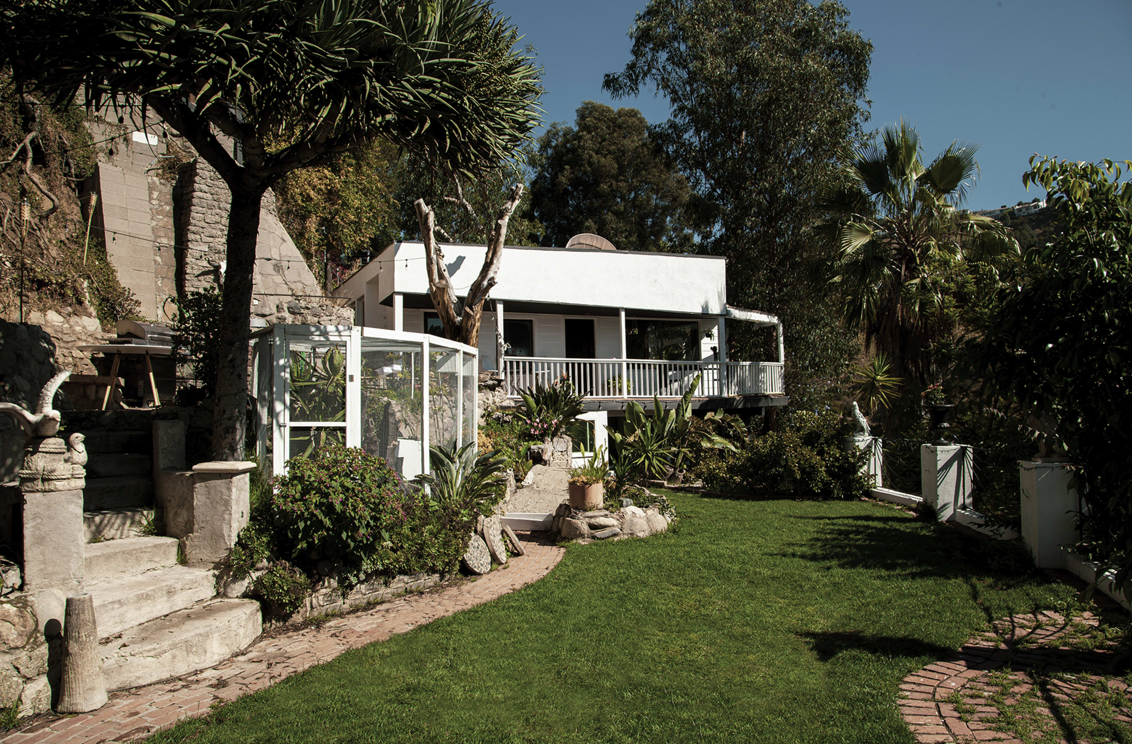 A garden with a well-maintained lawn, a modern house in the background, and decorative plants surrounding stone pathways.