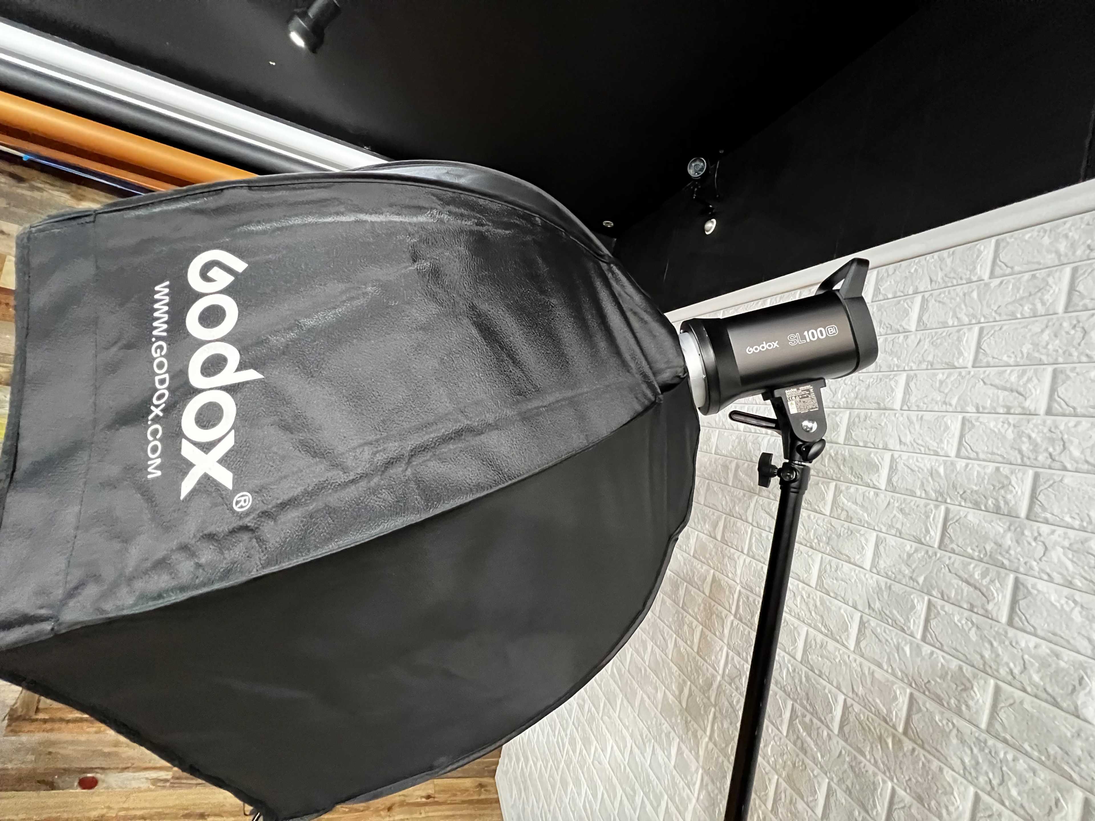 A Godox softbox attached to a studio light on a stand, with a textured white wall in the background.