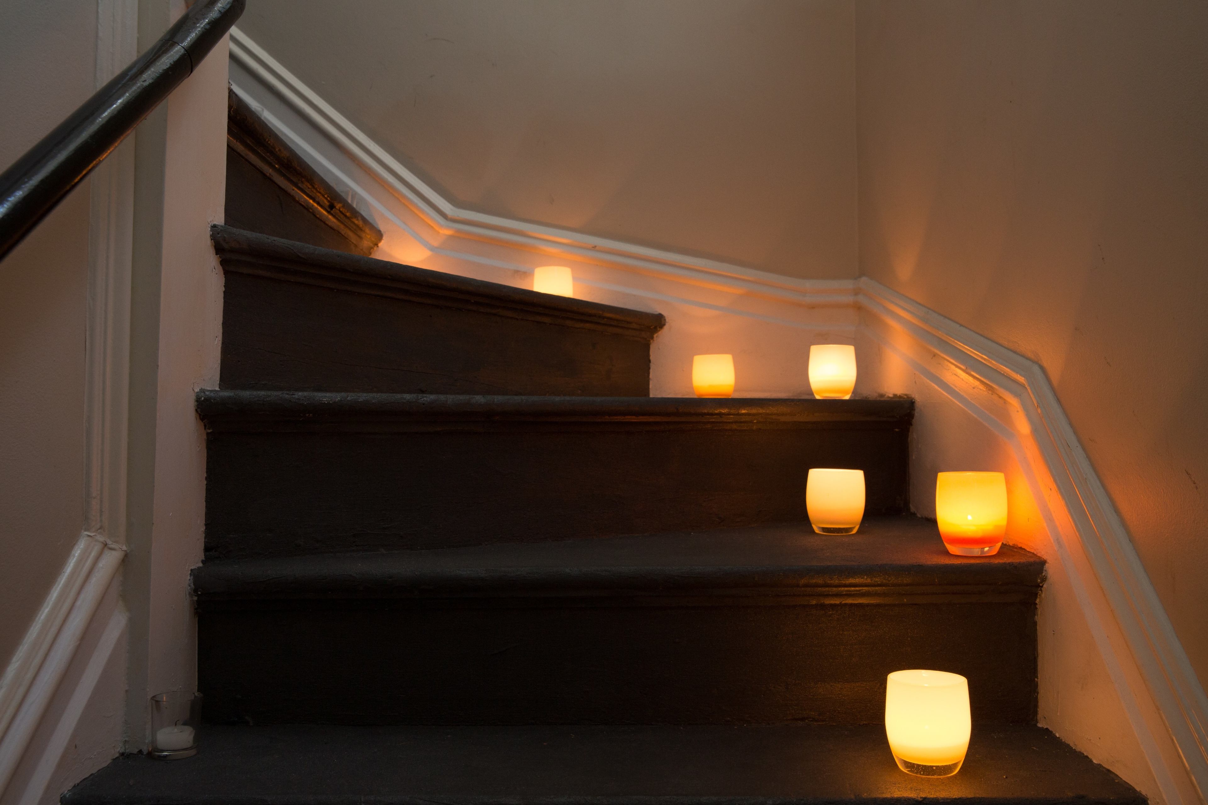 Candles are placed along the steps of a dimly lit staircase.