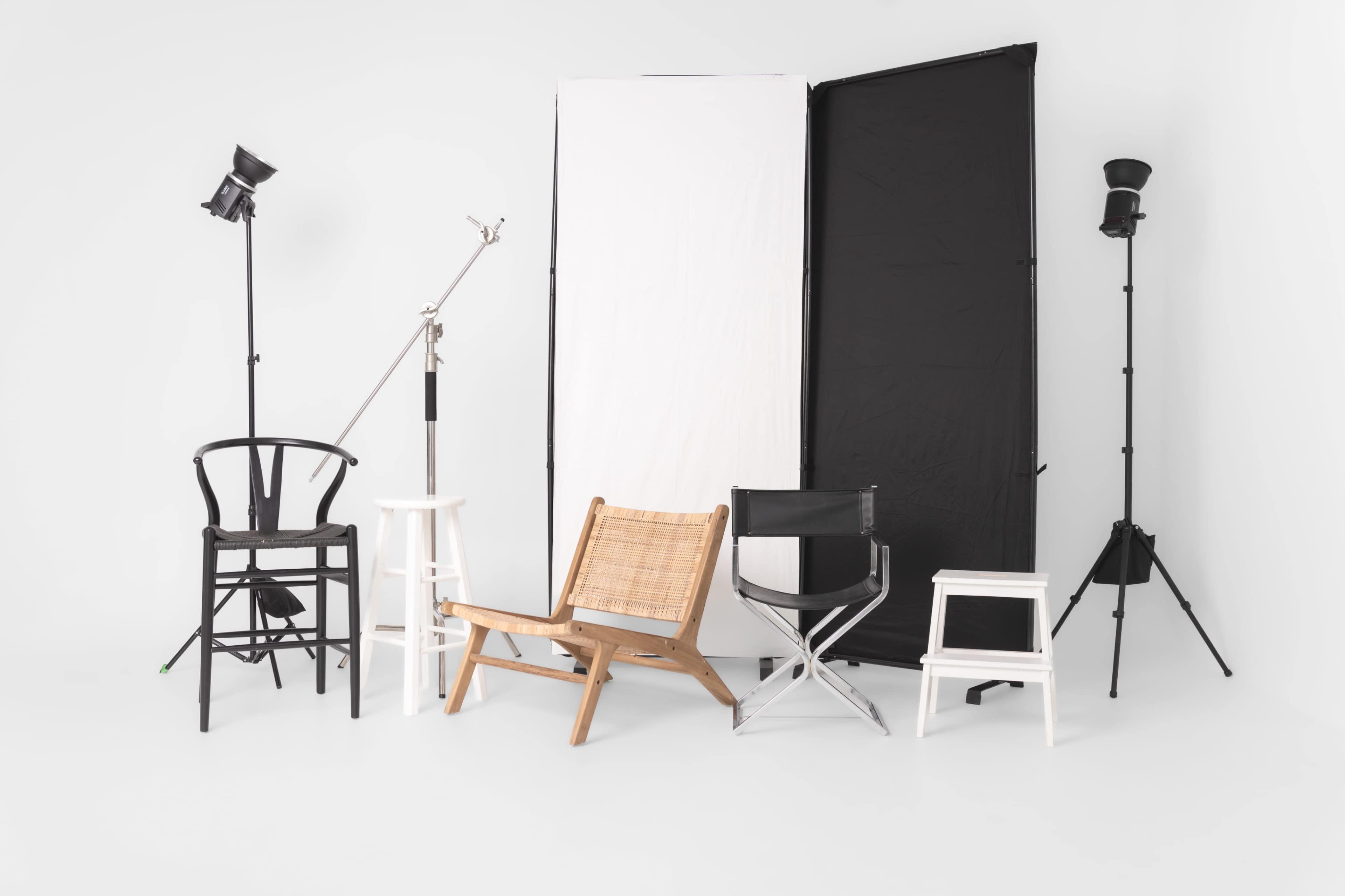 The image shows a variety of chairs arranged in a studio setting, accompanied by backdrop panels and lighting equipment.