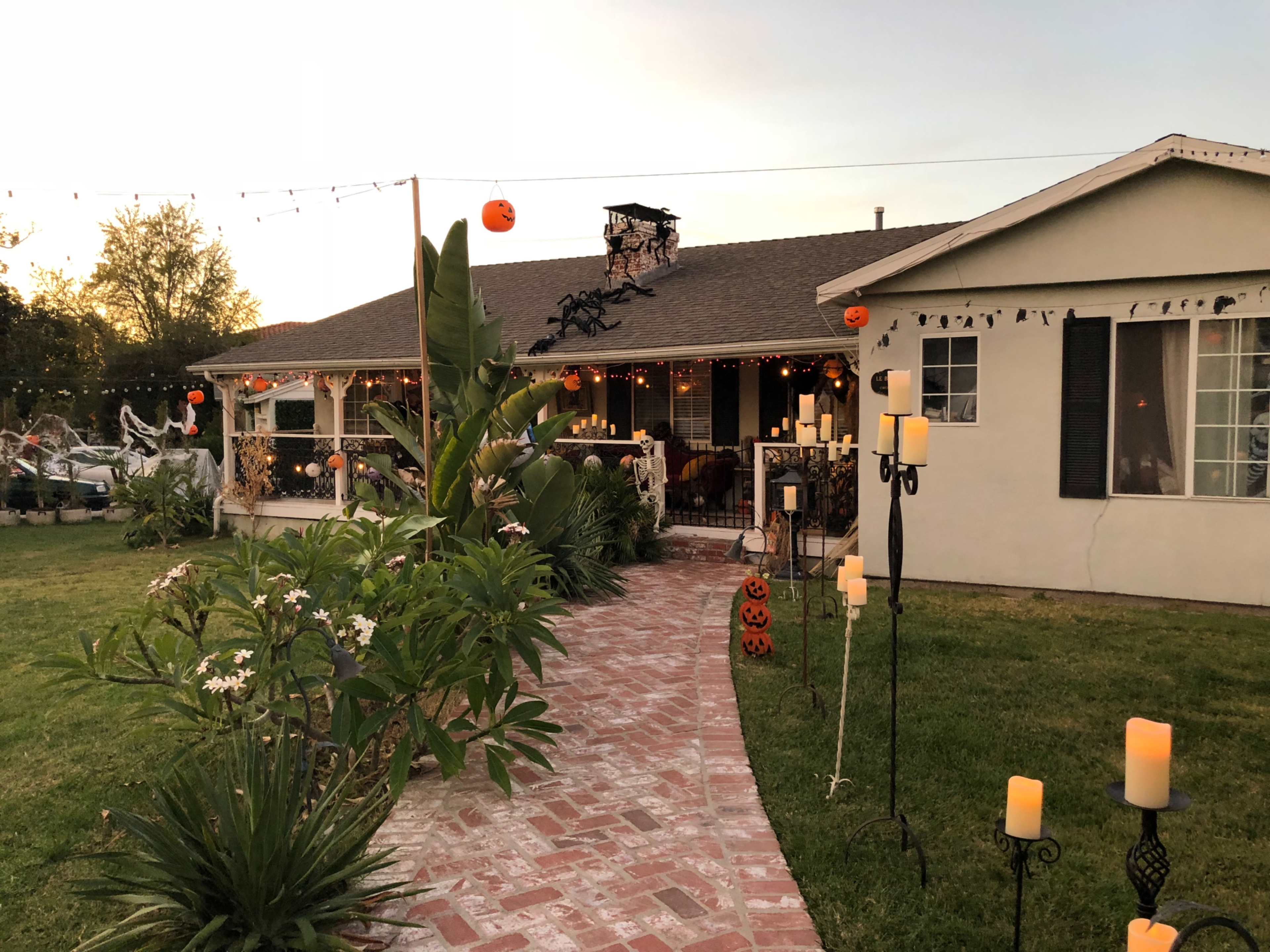 A pathway leads to a decorated house with Halloween-themed candles and pumpkins in the yard.