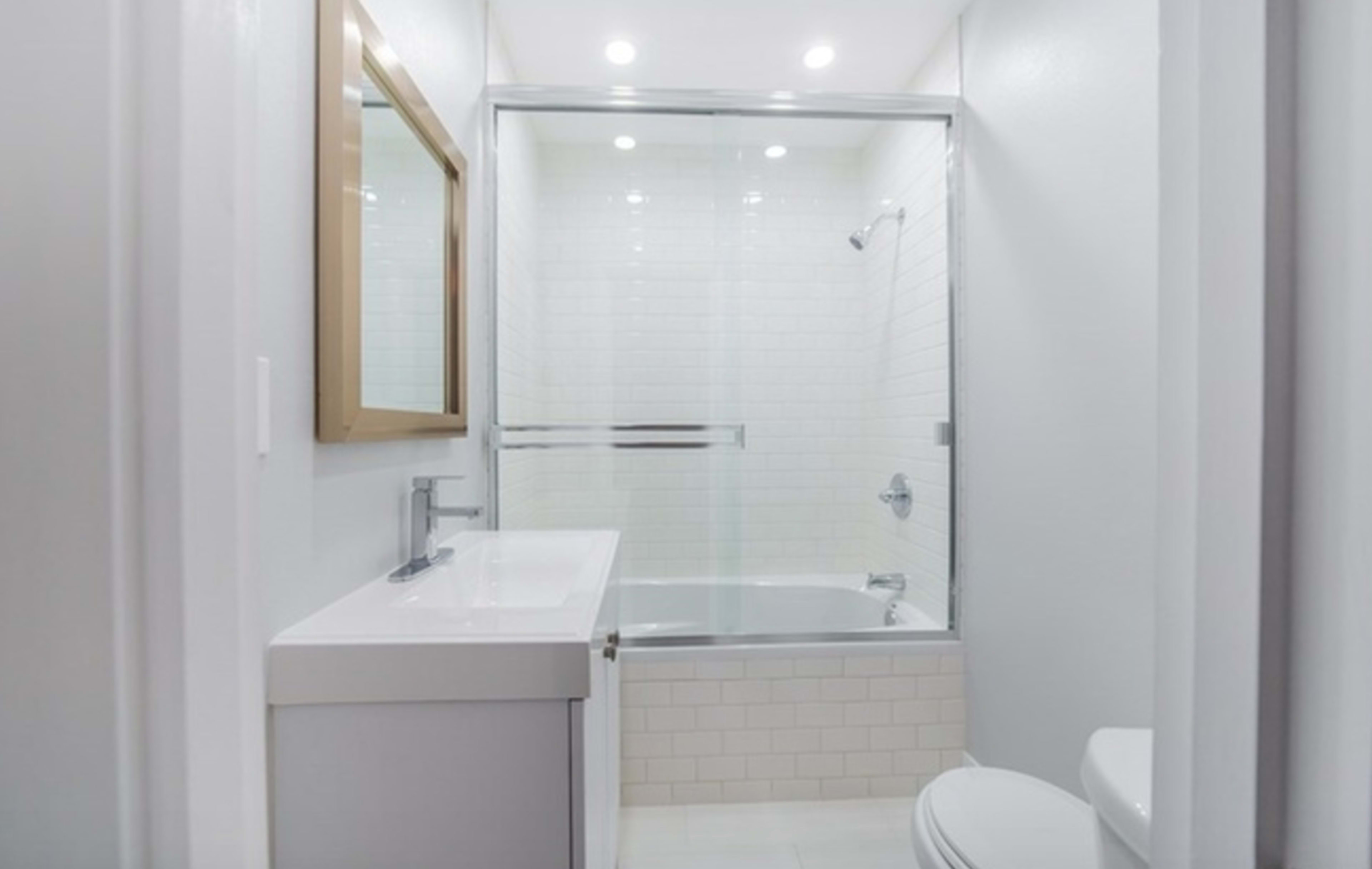 A modern bathroom featuring a glass shower enclosure, a white vanity with a sink, and a toilet.