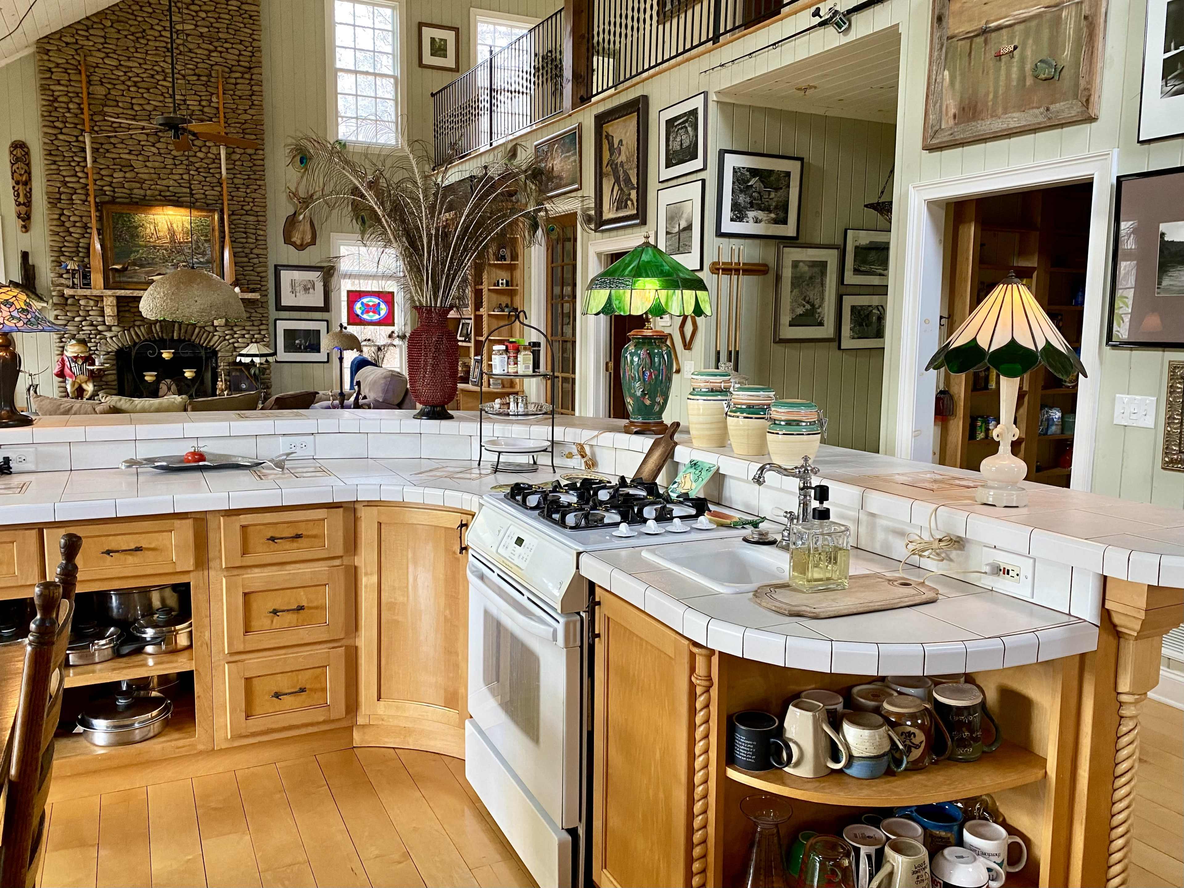 A spacious kitchen with a curved countertop, gas stove, and various decorative items, surrounded by numerous framed pictures on the walls.