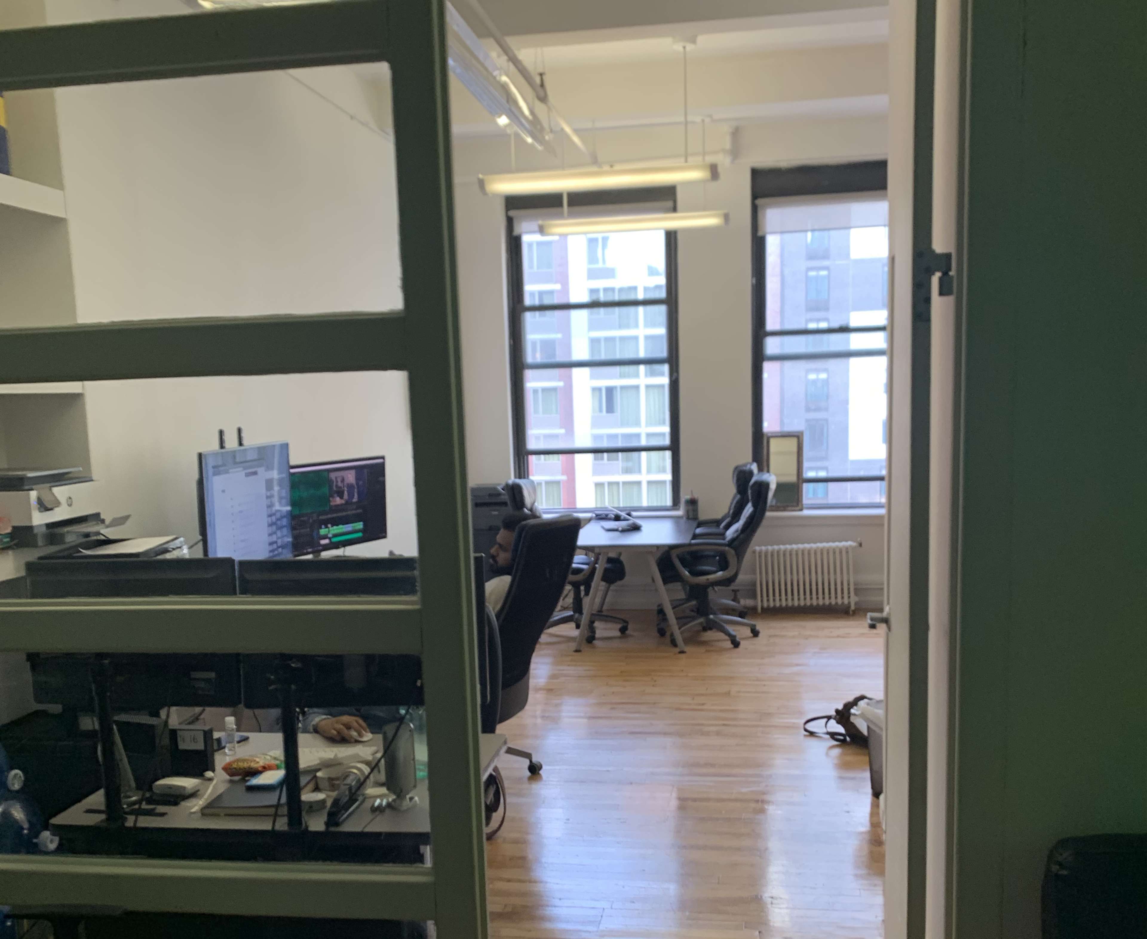 An office space with desks, computers, and chairs visible through a glass partition.