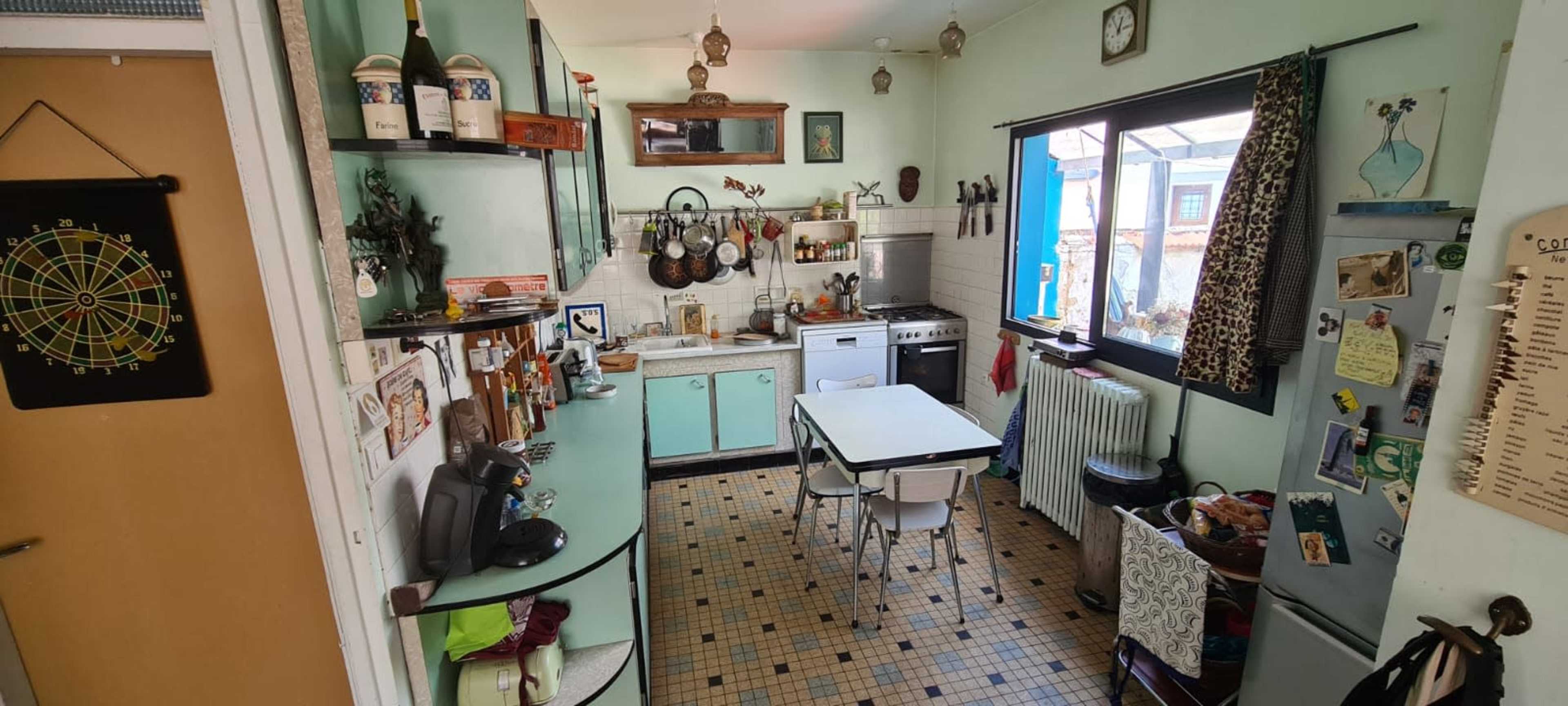 The image depicts a vintage-style kitchen with mint green cabinets, a stove, and a table surrounded by chairs.