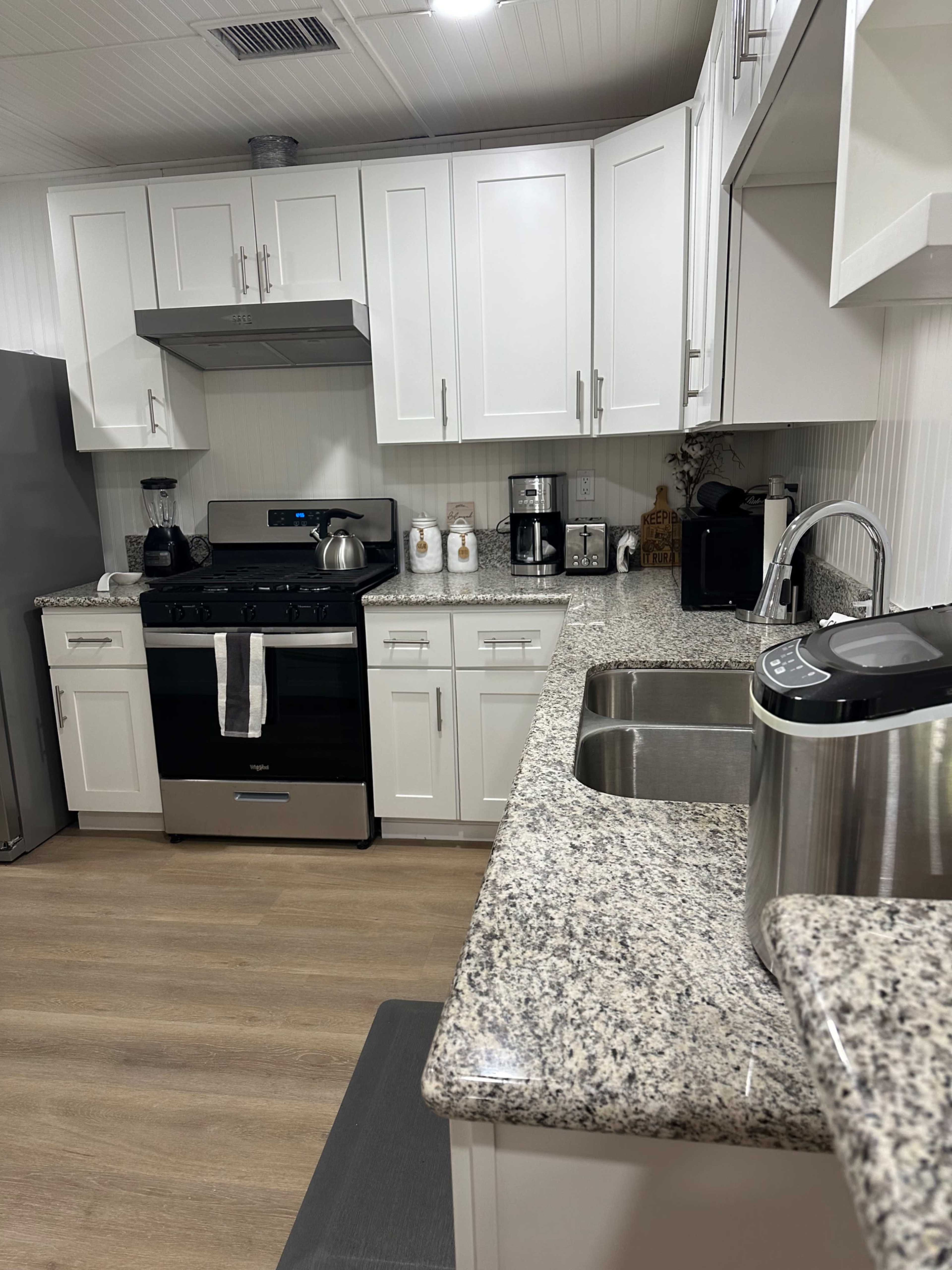 The kitchen features white cabinetry, granite countertops, and stainless steel appliances, including a stove and a sink.