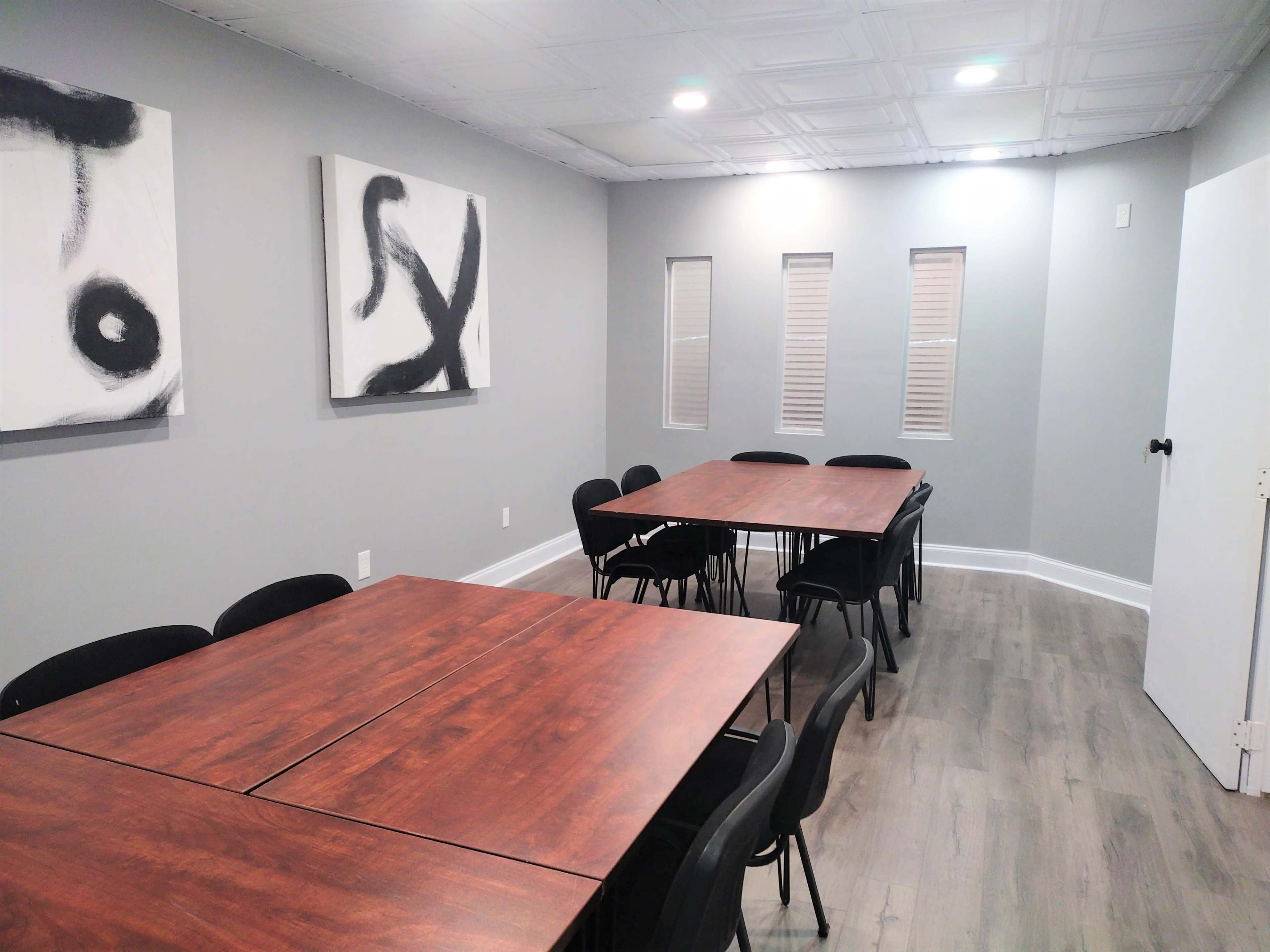 A meeting room with two large tables arranged for seating and abstract art on the walls.