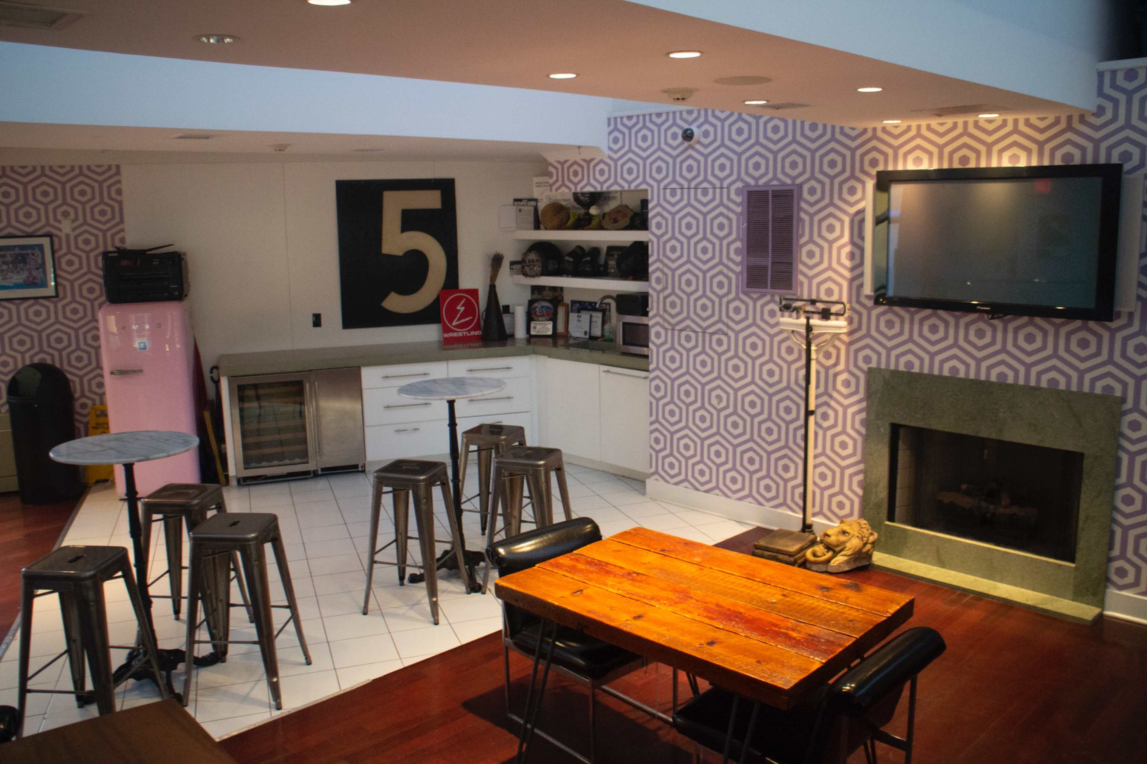 A modern kitchen and dining area featuring a pink refrigerator, a gas fireplace, and a patterned wall with a large number 5 displayed.