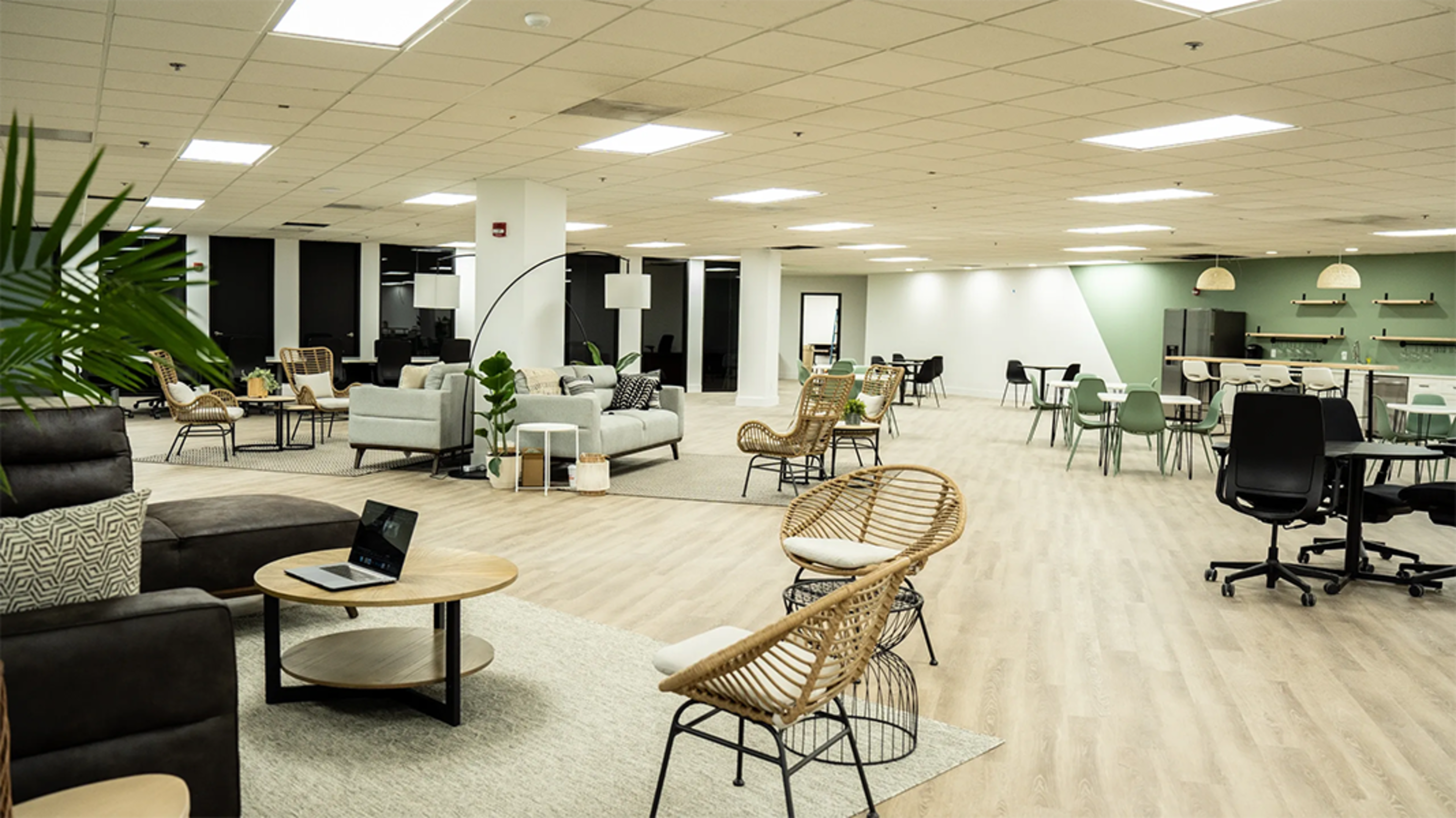 A modern office space filled with various seating arrangements, including couches and chairs, along with workstations and decorative plants.