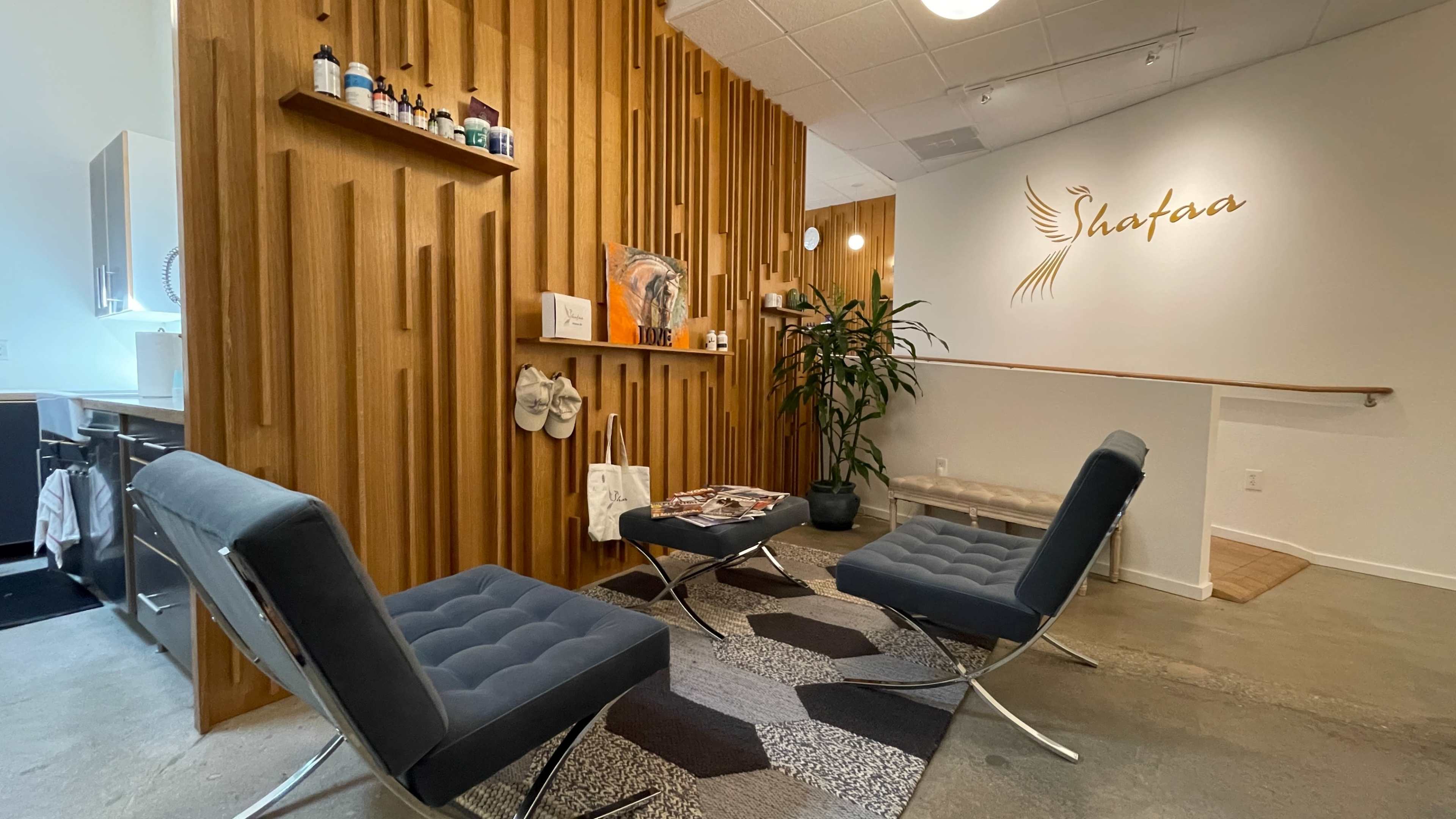 The image shows a welcoming reception area with wooden paneling, modern seating, and decorative plants in a wellness center.