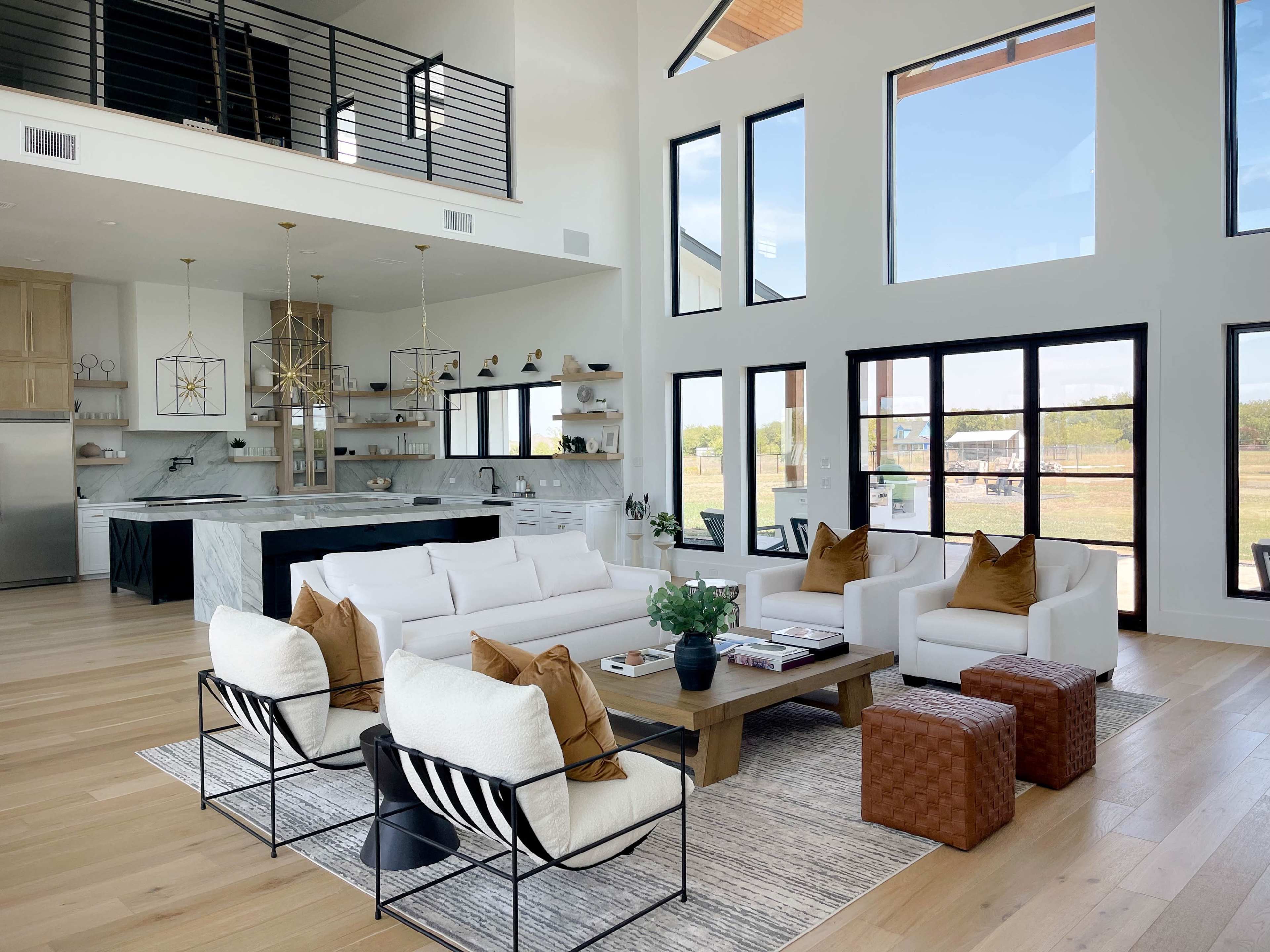 The image depicts a spacious modern living room with a white sectional sofa, a wooden coffee table, and large windows that allow natural light to fill the space.