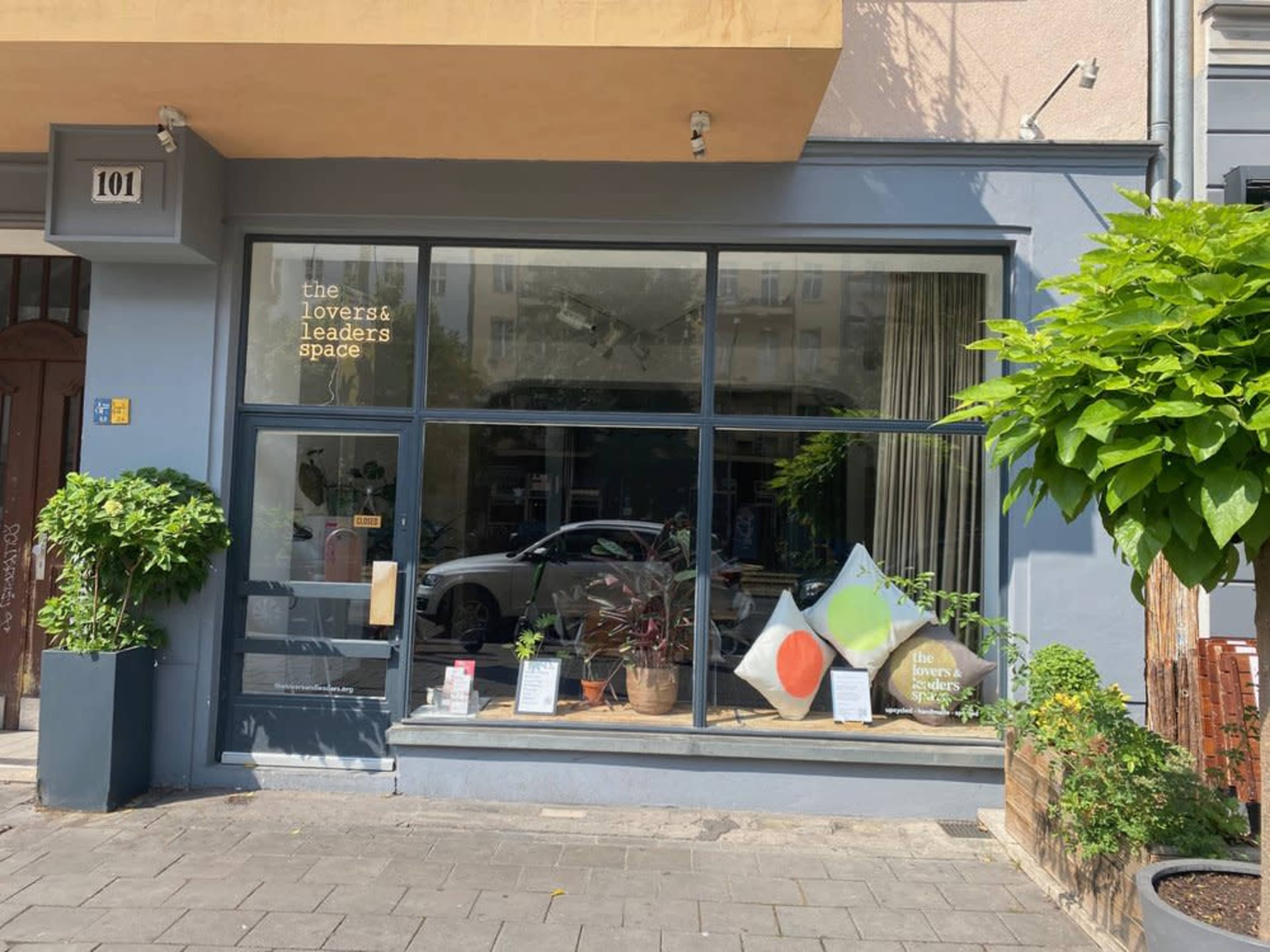 The storefront features large windows displaying plants and decorative cushions, with the text "the lovers & leaders space" visible on the glass.