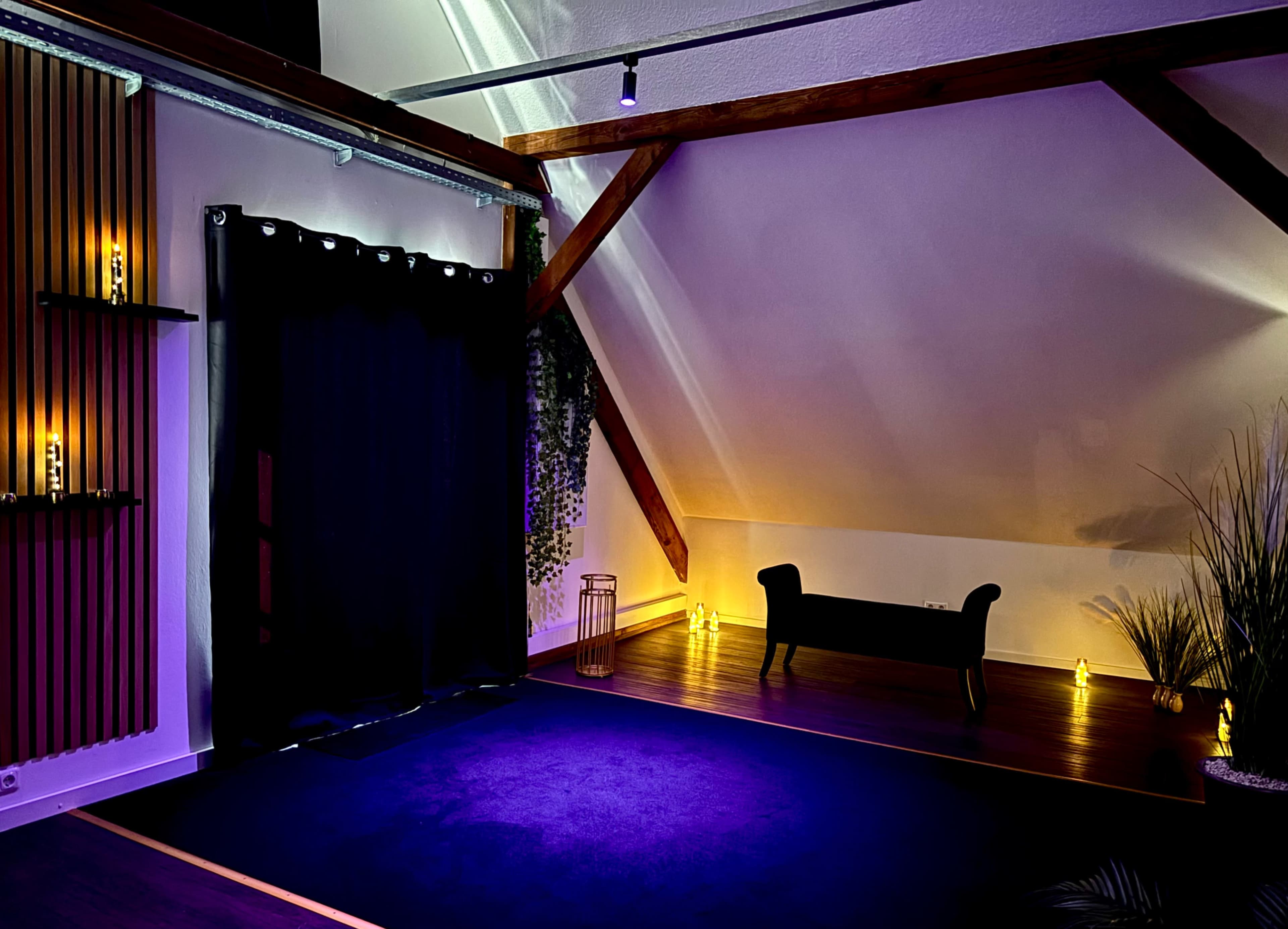 The image features a room with wooden beams, a dark curtain, a seated area, and ambient lighting creating a tranquil atmosphere.