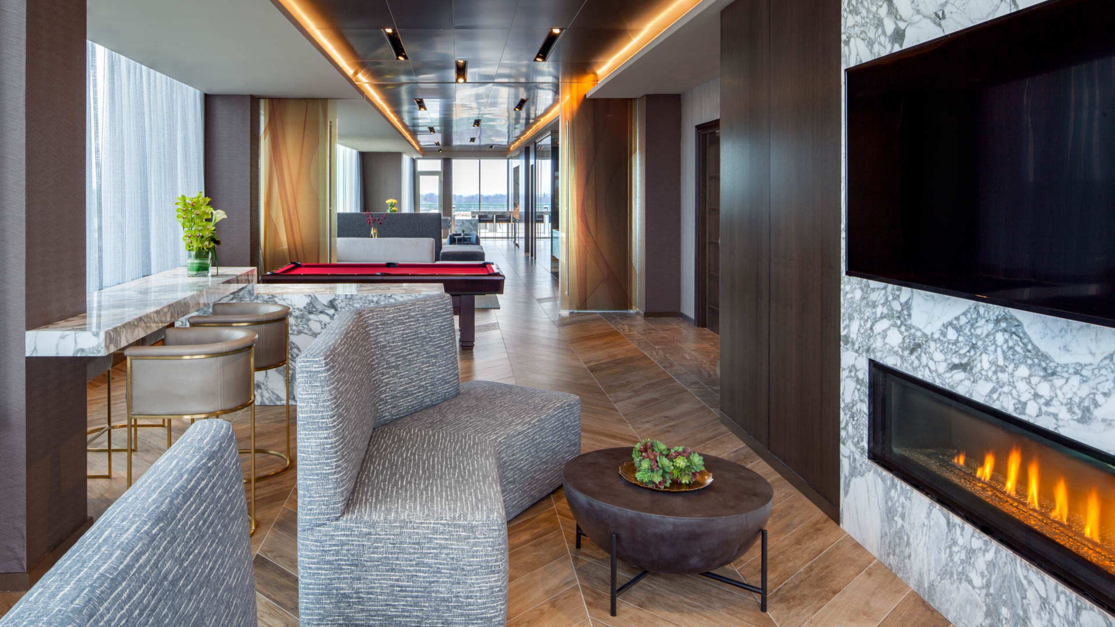 A modern interior lounge with a pool table, a fireplace, and large windows offering a view.