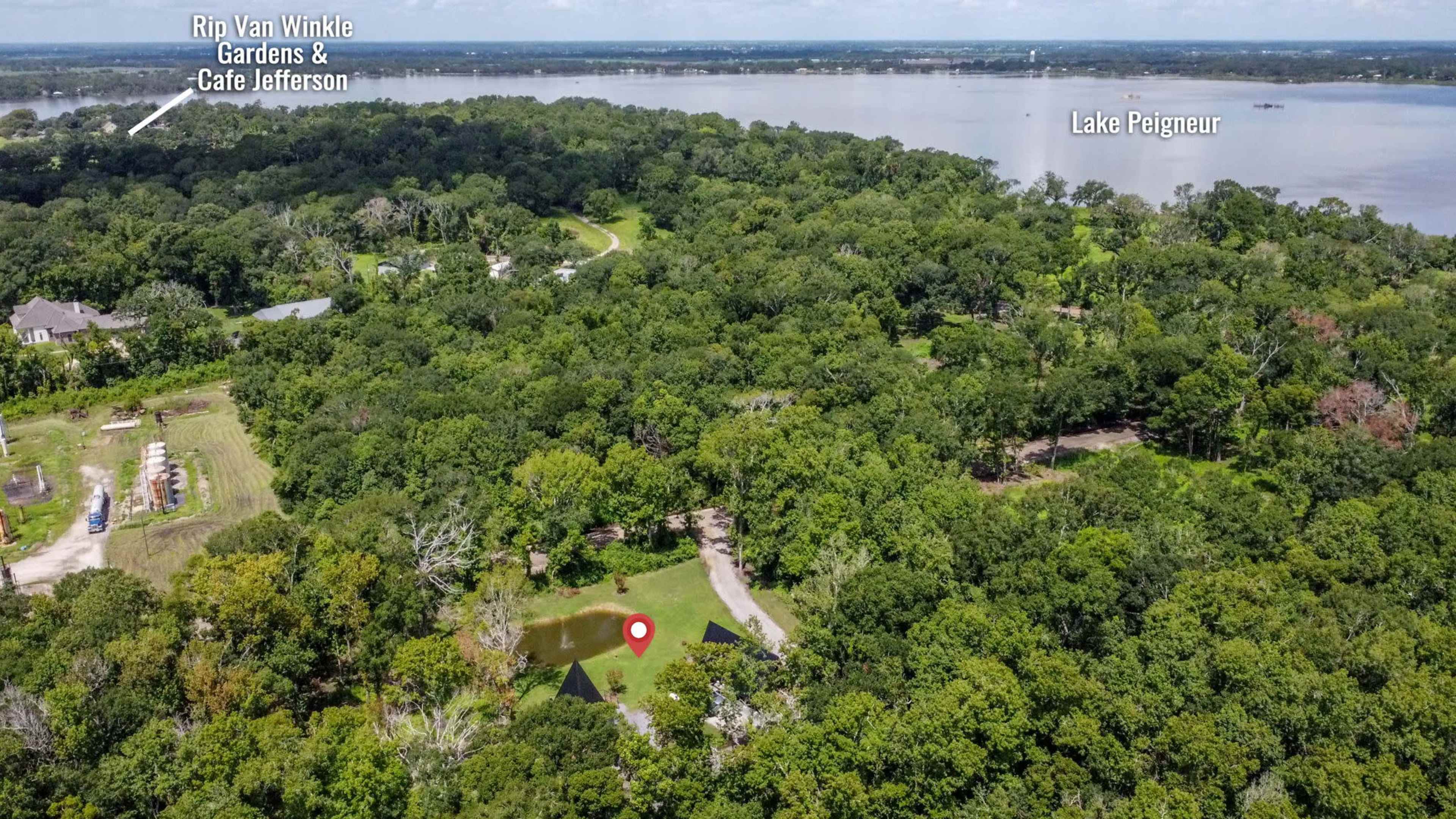 An aerial view shows a green landscape surrounding a small pond, with Lake Peigneur visible in the background.