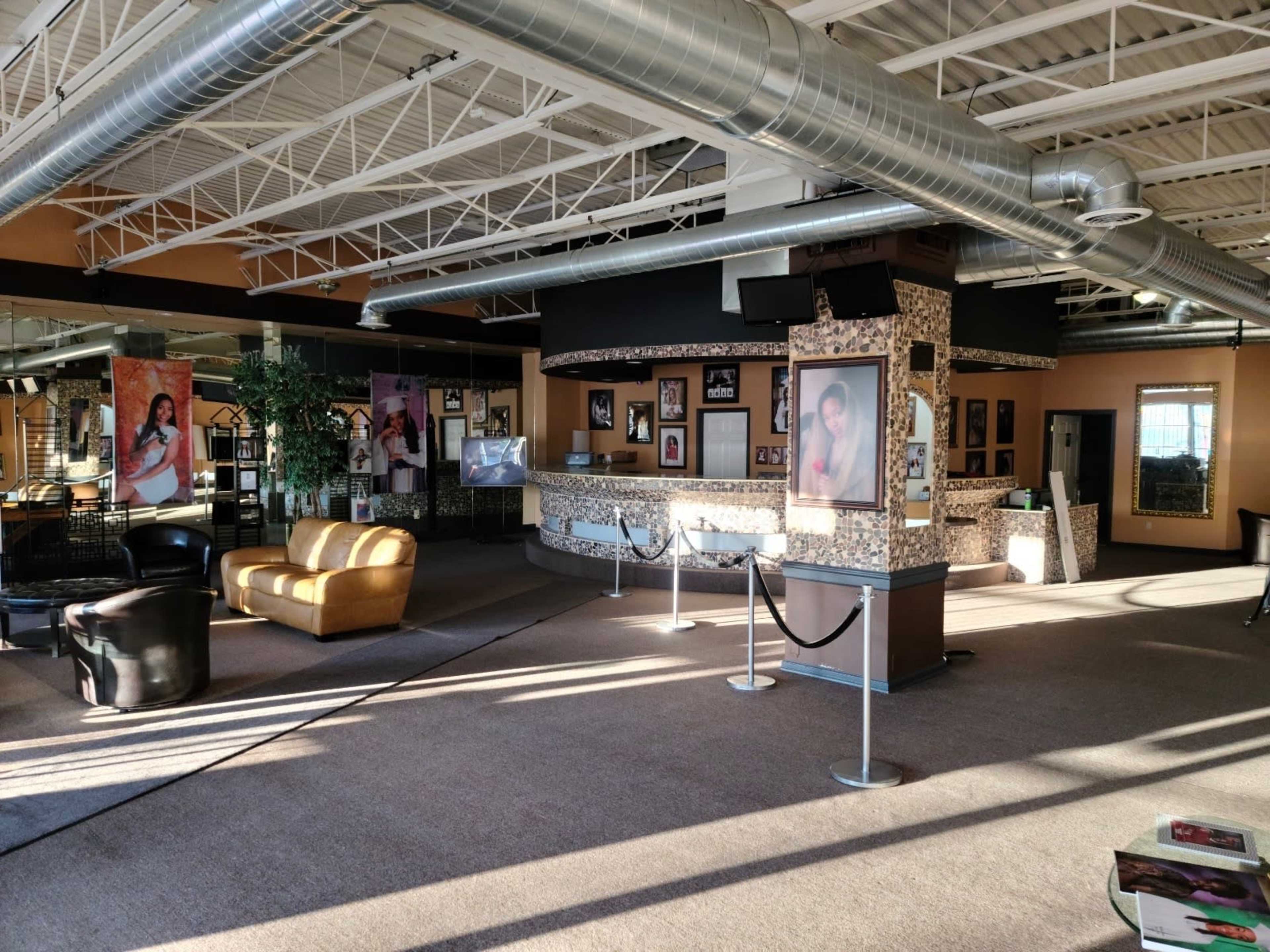 The image shows a spacious interior with a reception area featuring artwork on the walls, seating arrangements, and a layout that includes a counter and open space.