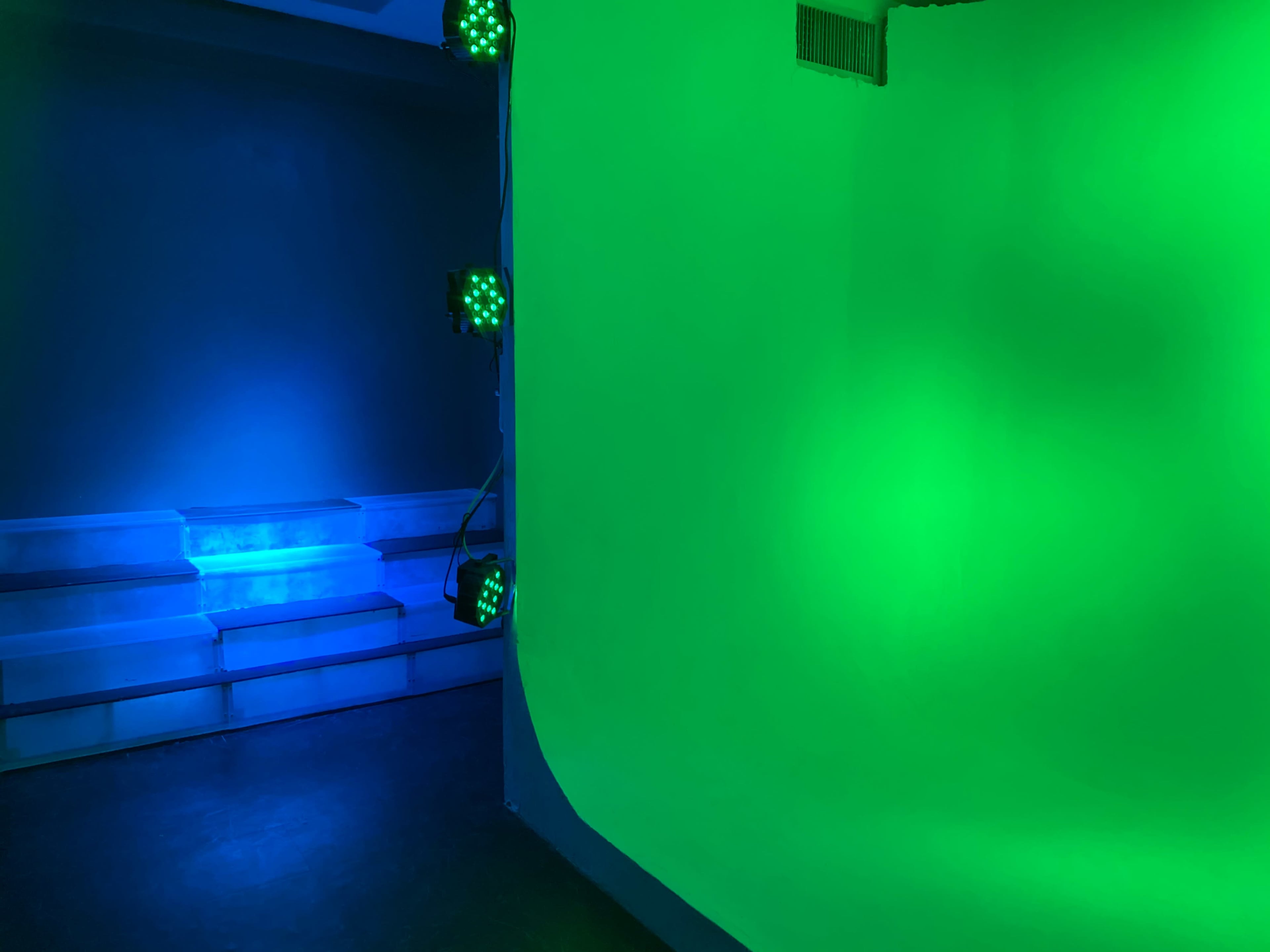 A split scene with a blue-lit area on the left and a green-lit backdrop on the right, creating a contrasting color scheme in a studio setting.