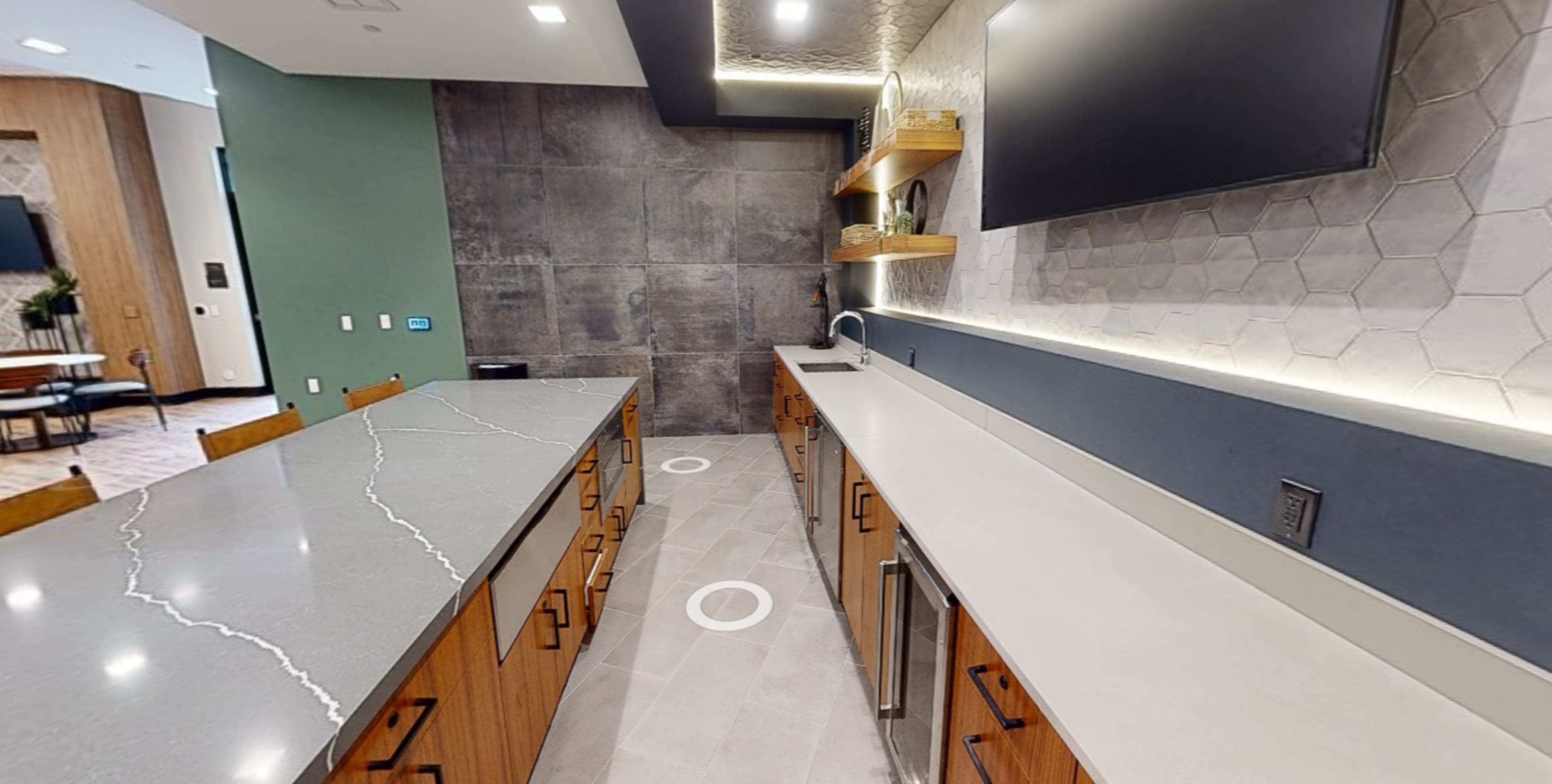 The image shows a modern kitchen with gray stone countertops, wooden cabinets, and a hexagonal tile backsplash.
