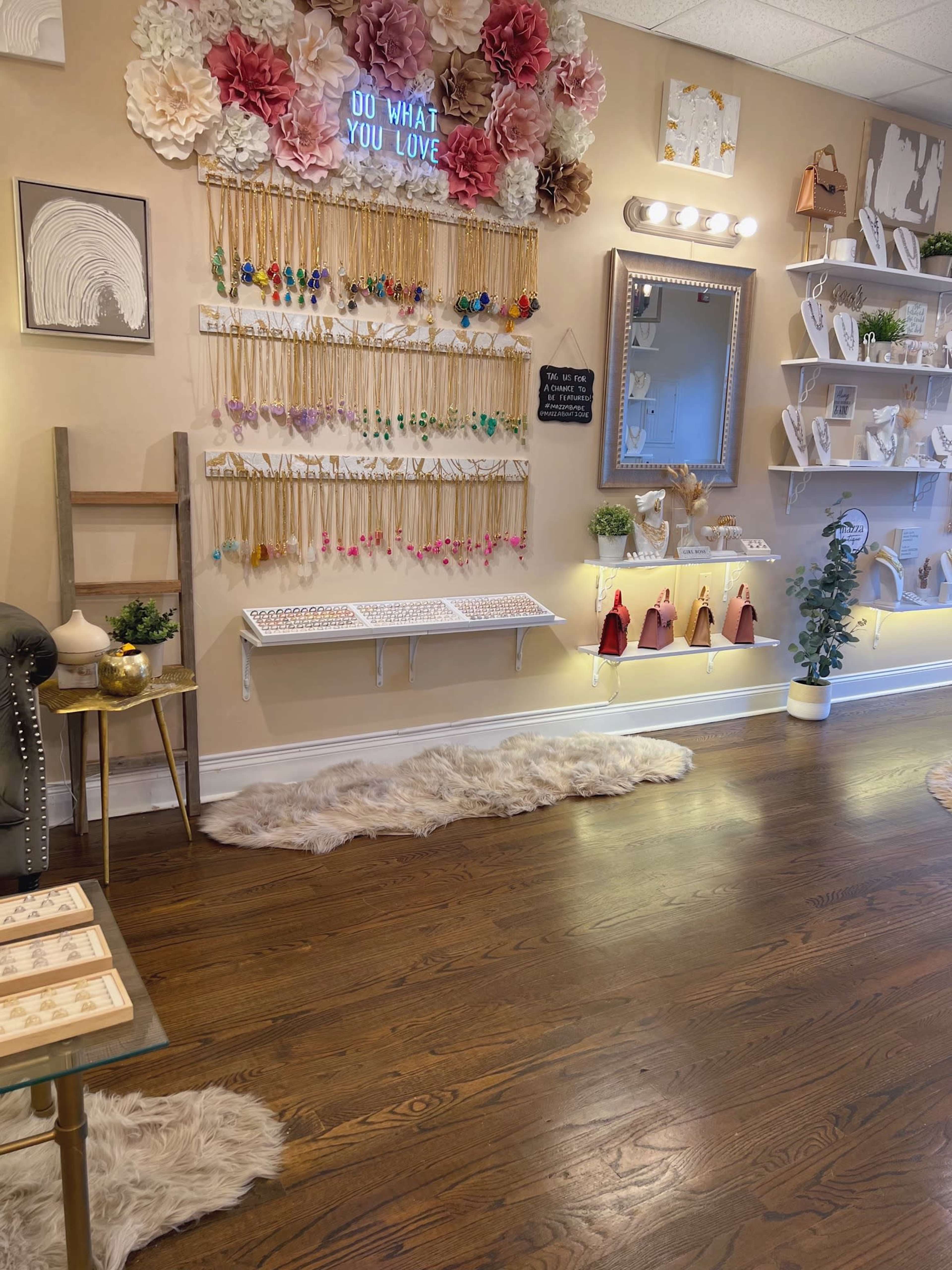 A retail space with a decorated wall displaying jewelry and decorative elements, along with wooden furniture and a stylish mirror.