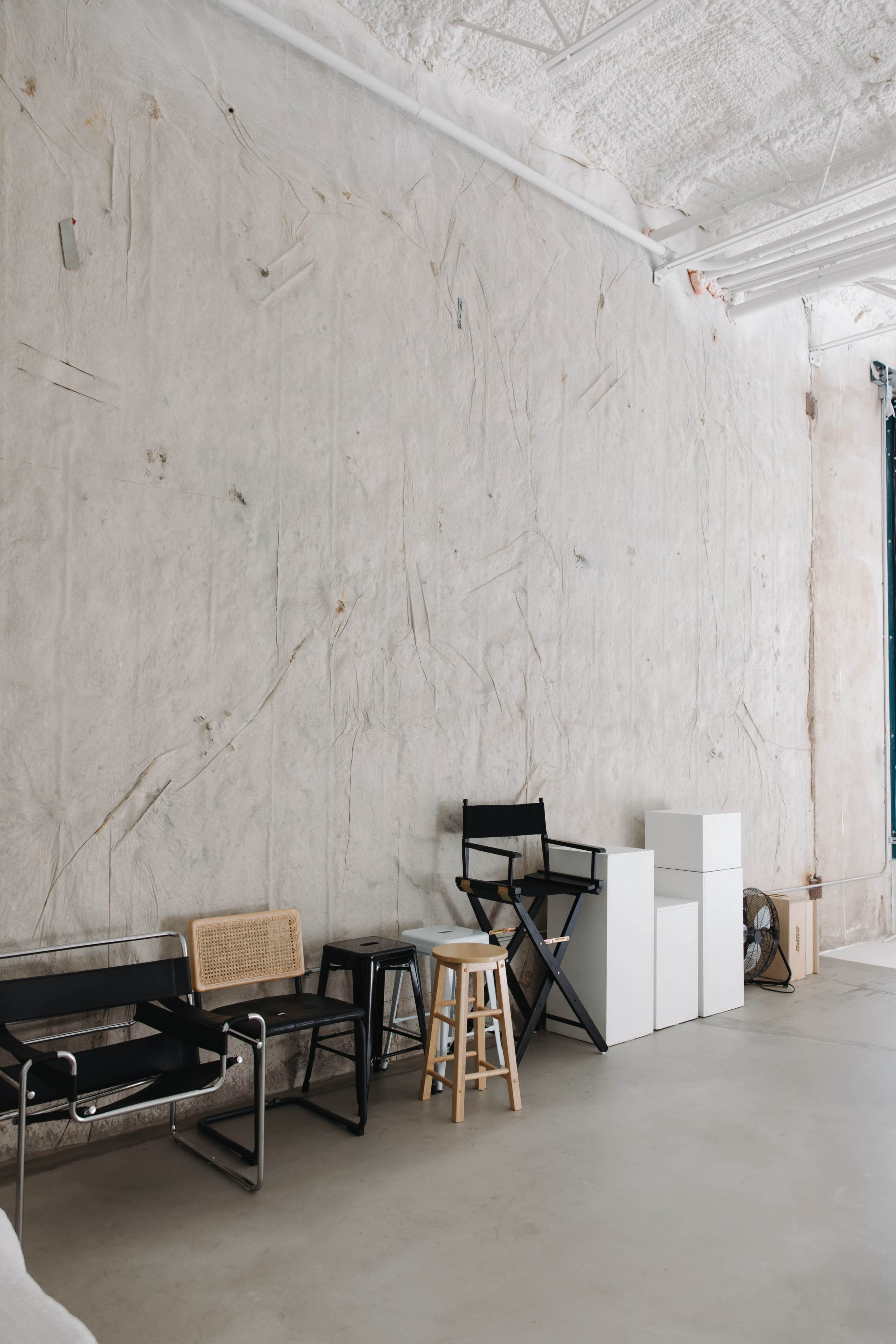 A minimalist interior features a textured wall with various seating options and white storage units arranged along the floor.