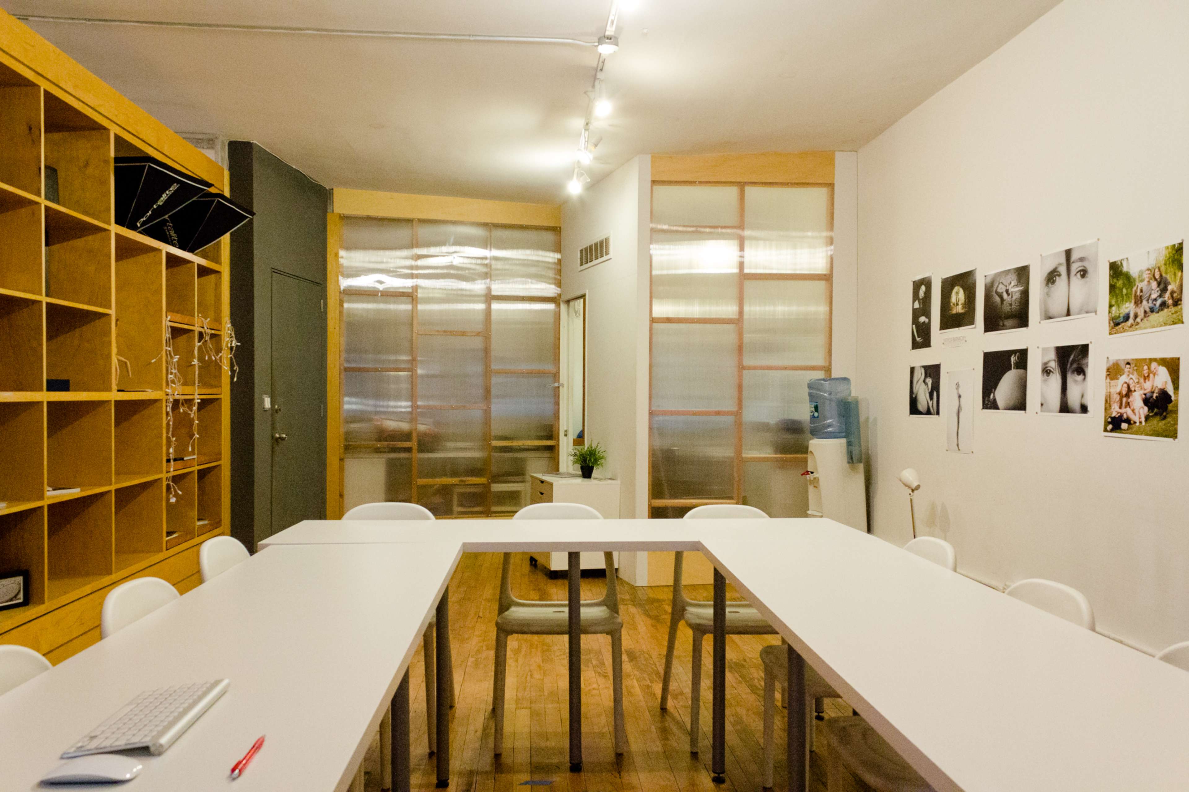 A large, white conference table is set up in a well-lit room filled with wooden shelves and photographs on the walls.