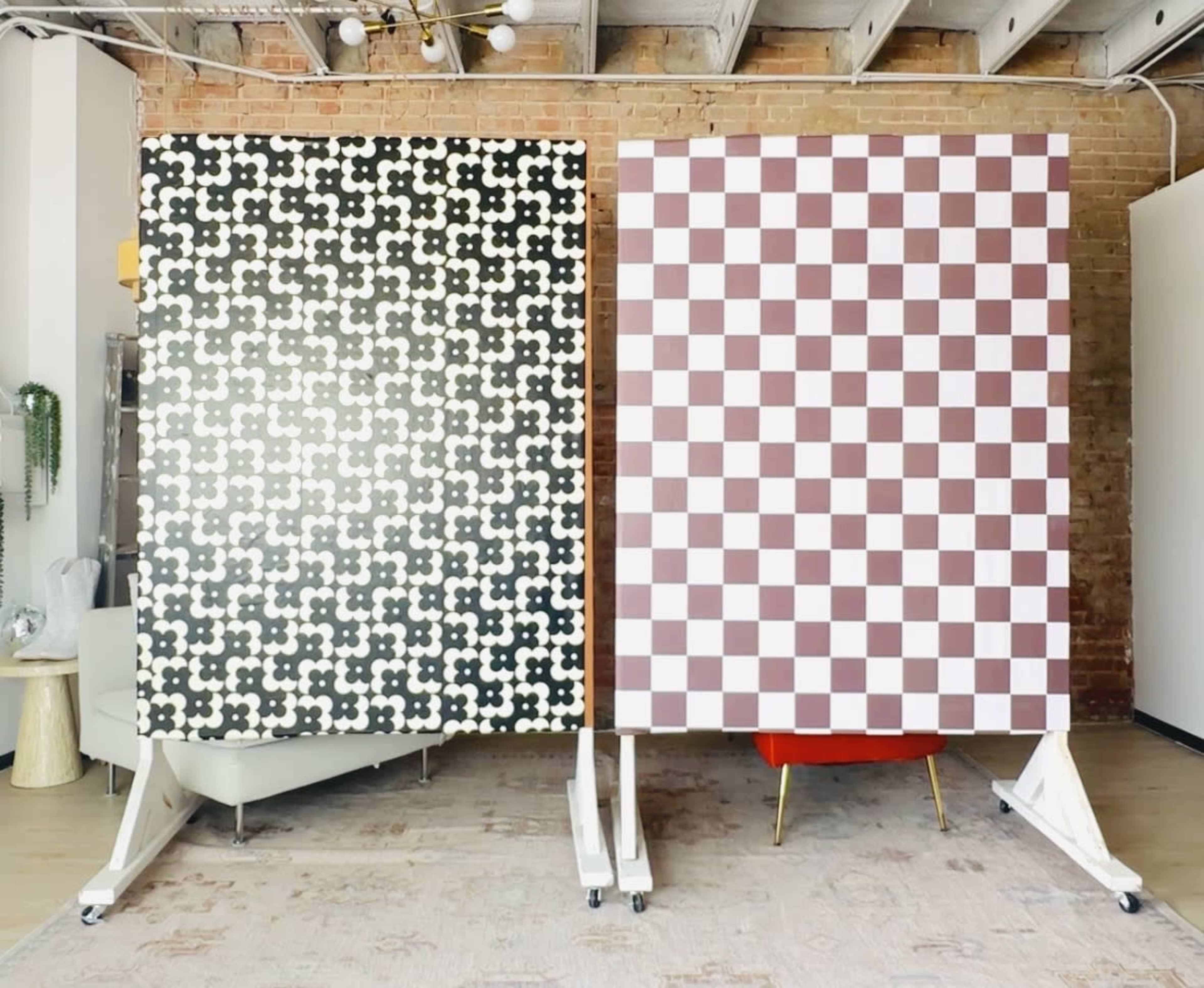 The image shows two large panels on wheels; one features a black and white patterned design, while the other displays a red and white checkered pattern.