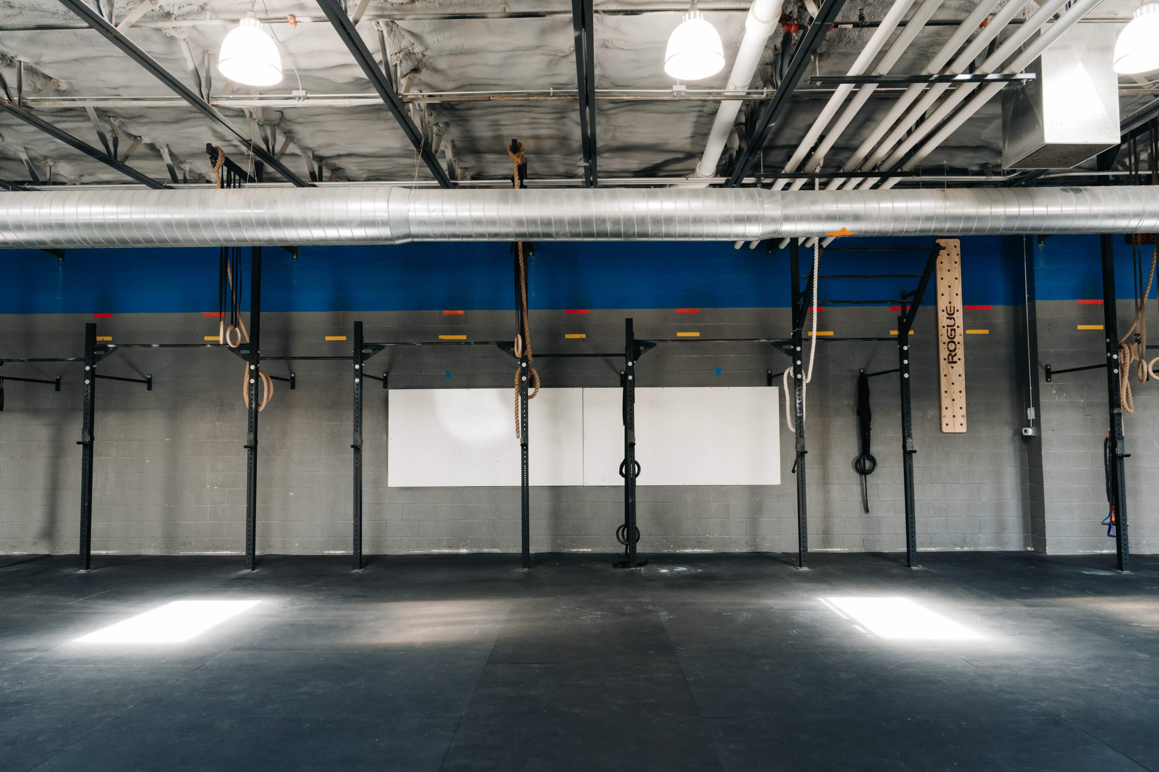 The image shows a spacious gym interior with multiple pull-up bars, gymnastic rings, and a clear workout area.