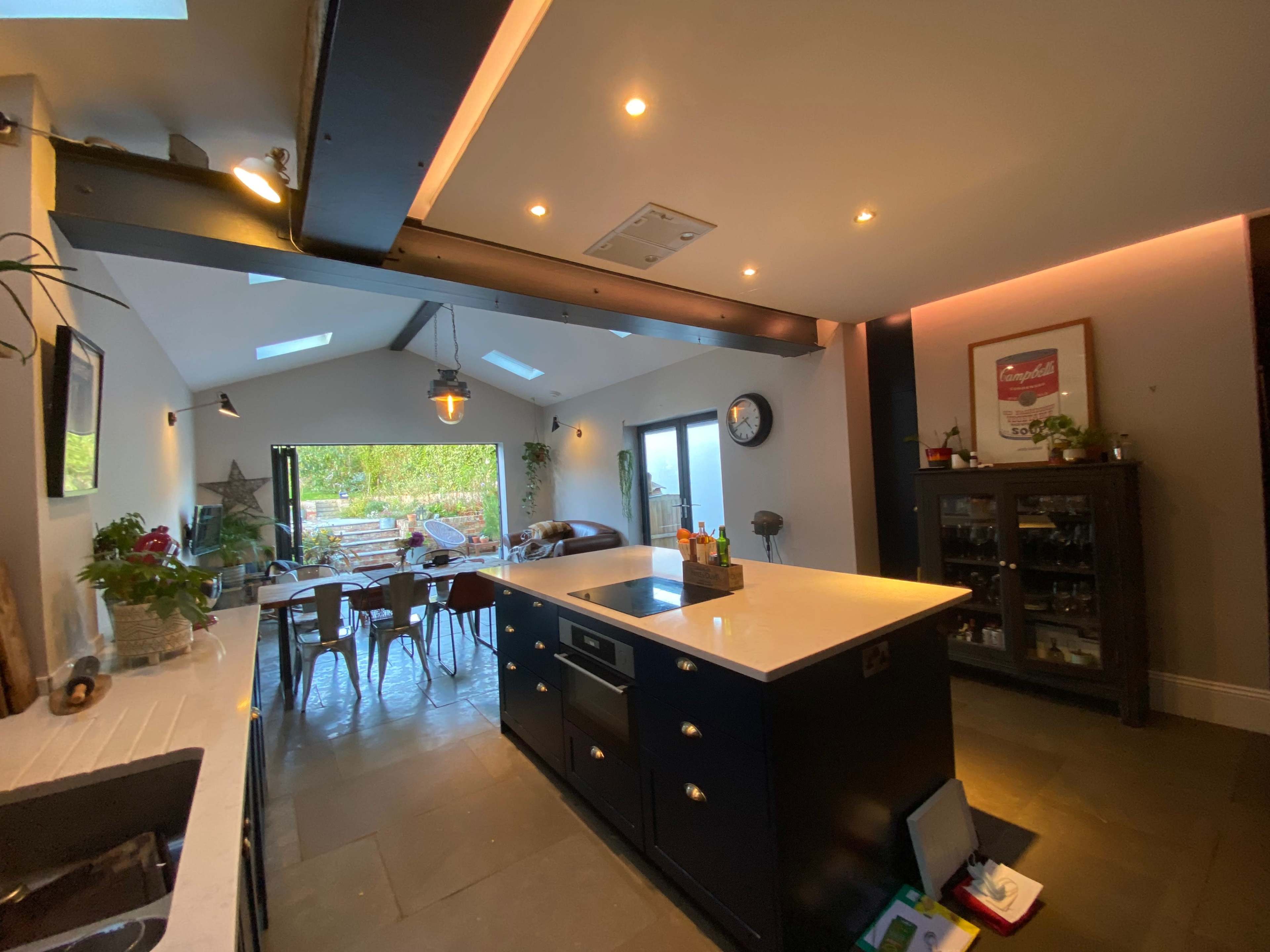 A modern kitchen with an island, featuring sleek cabinetry and open access to a dining area with wooden furniture.