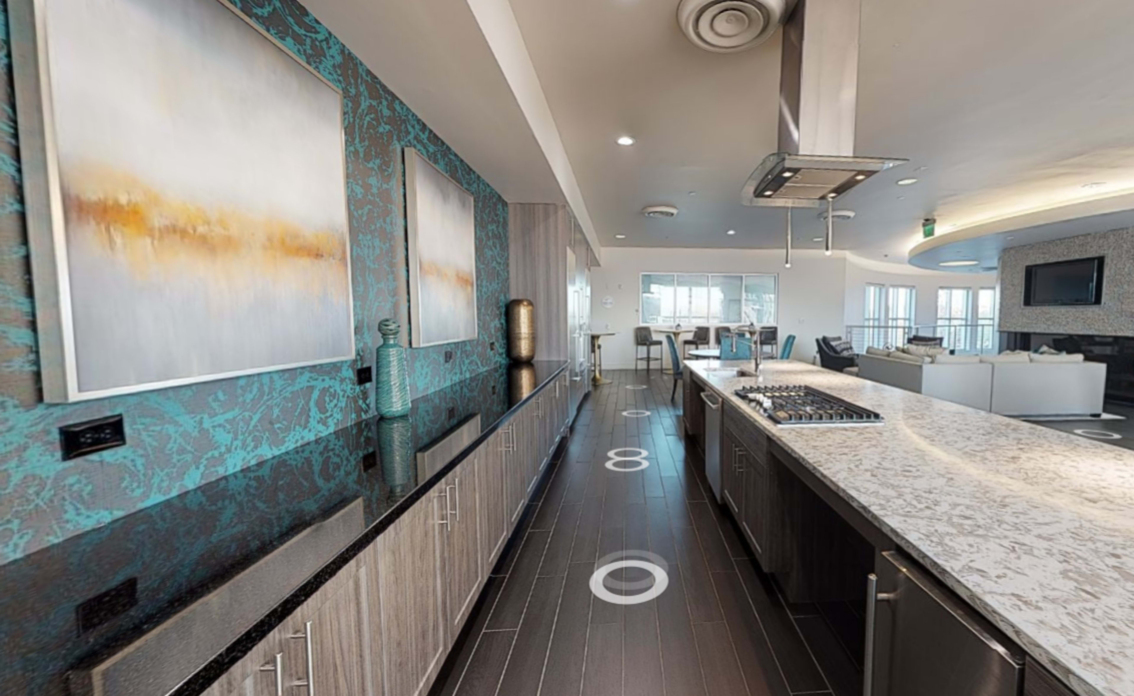 A modern kitchen features granite countertops, stainless steel appliances, and decorative wall art with a turquoise backdrop.