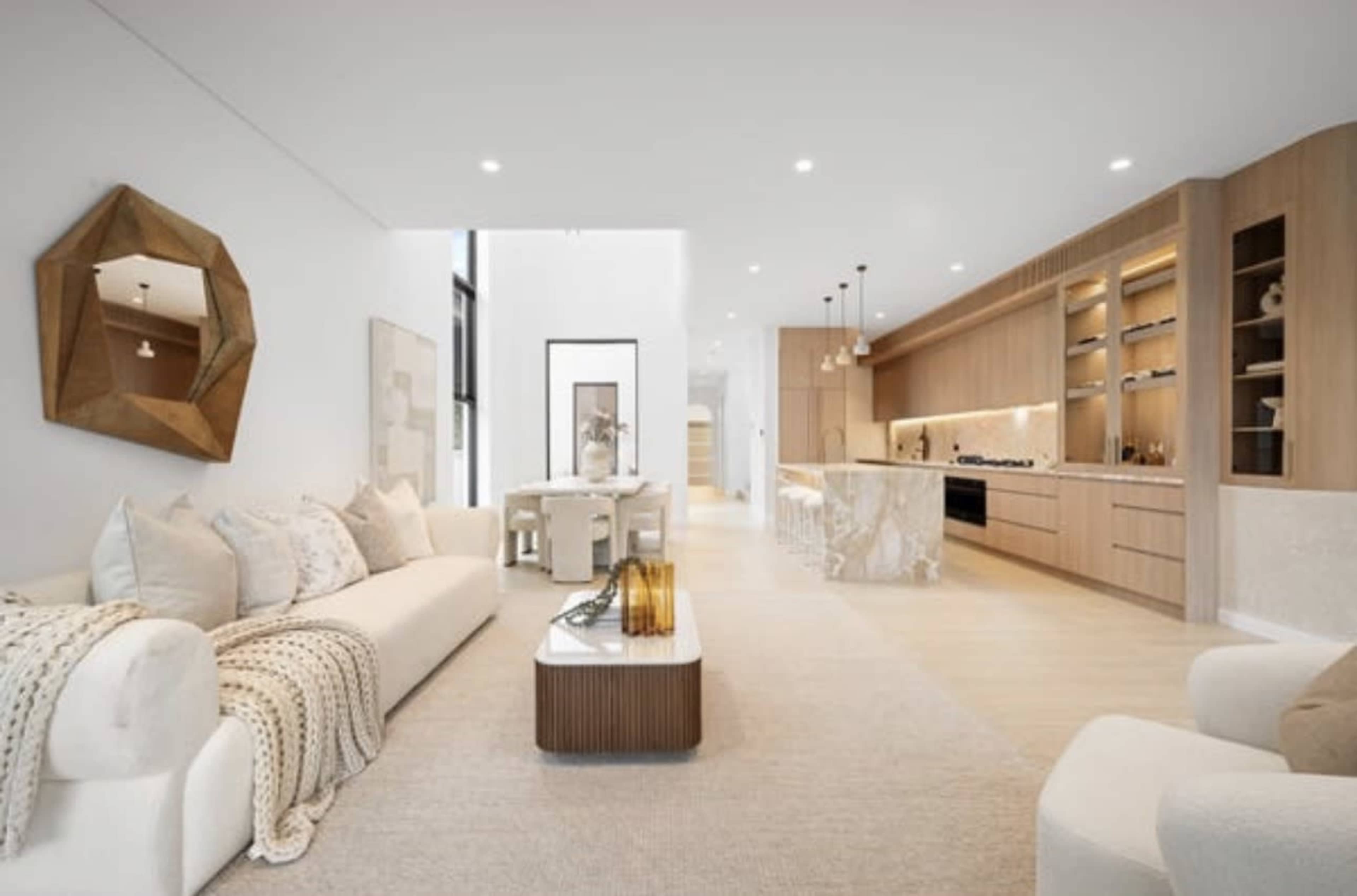 The image shows a modern, open-concept living space featuring a beige sofa, a dining area, and a kitchen with wooden cabinetry and bar seating.