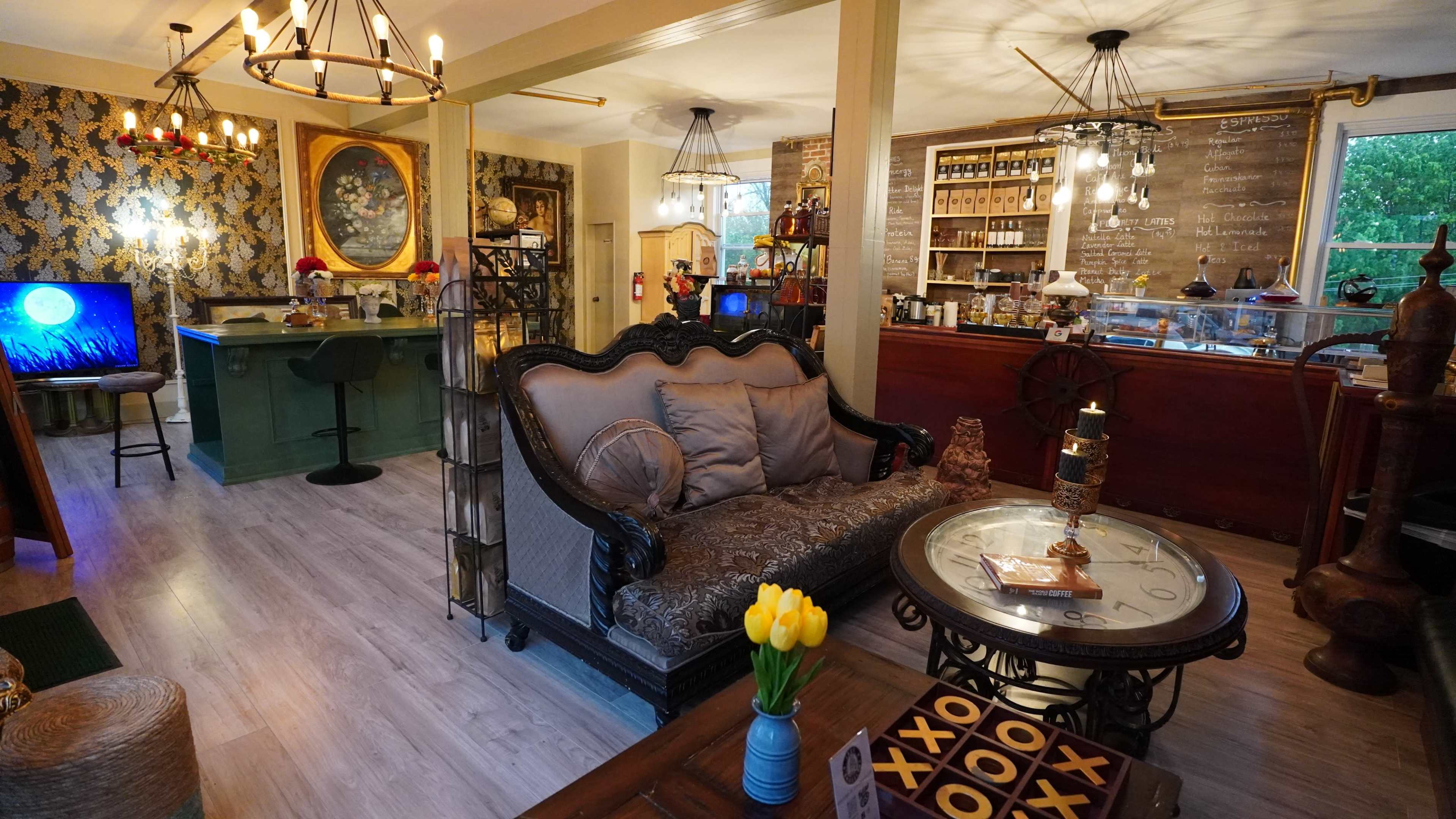 A cozy café interior with a mix of vintage furnishings, bar seating, and decorative wall elements.