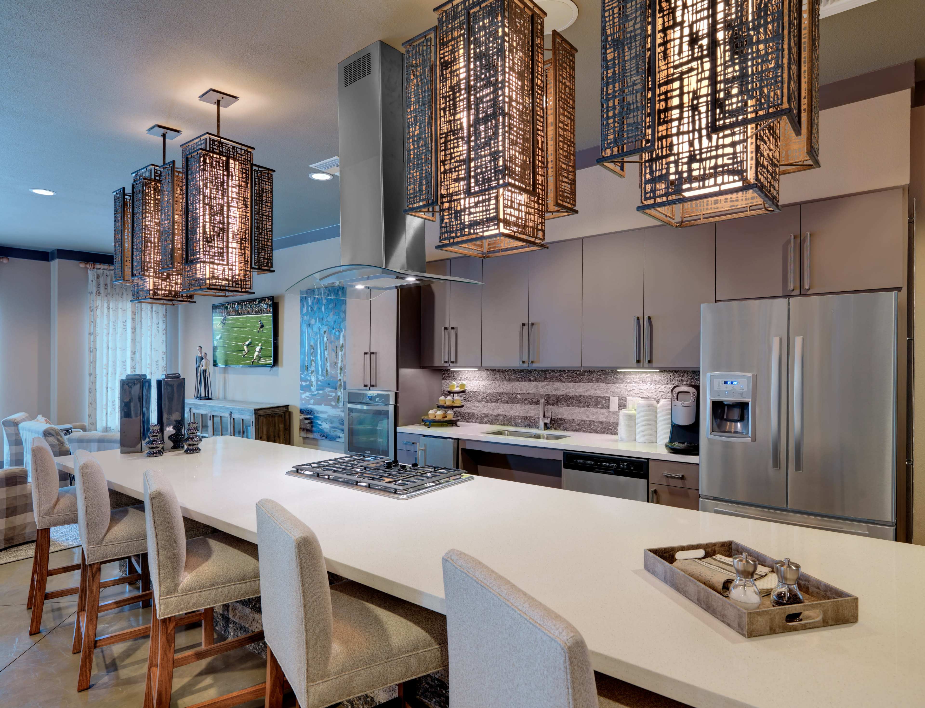 The image shows a modern kitchen with a large island, featuring pendant lights and contemporary appliances.