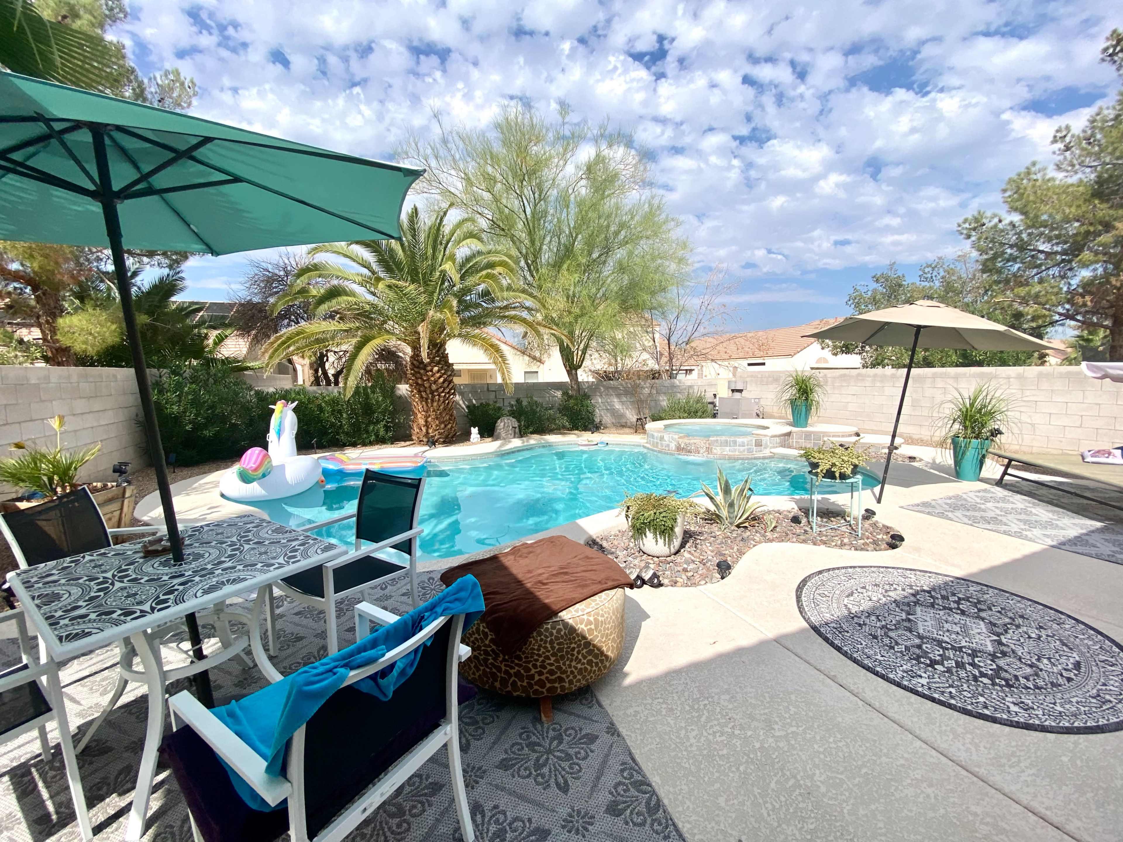 The scene features a backyard pool area with a turquoise swimming pool, lounge chairs, an umbrella, and surrounding greenery.