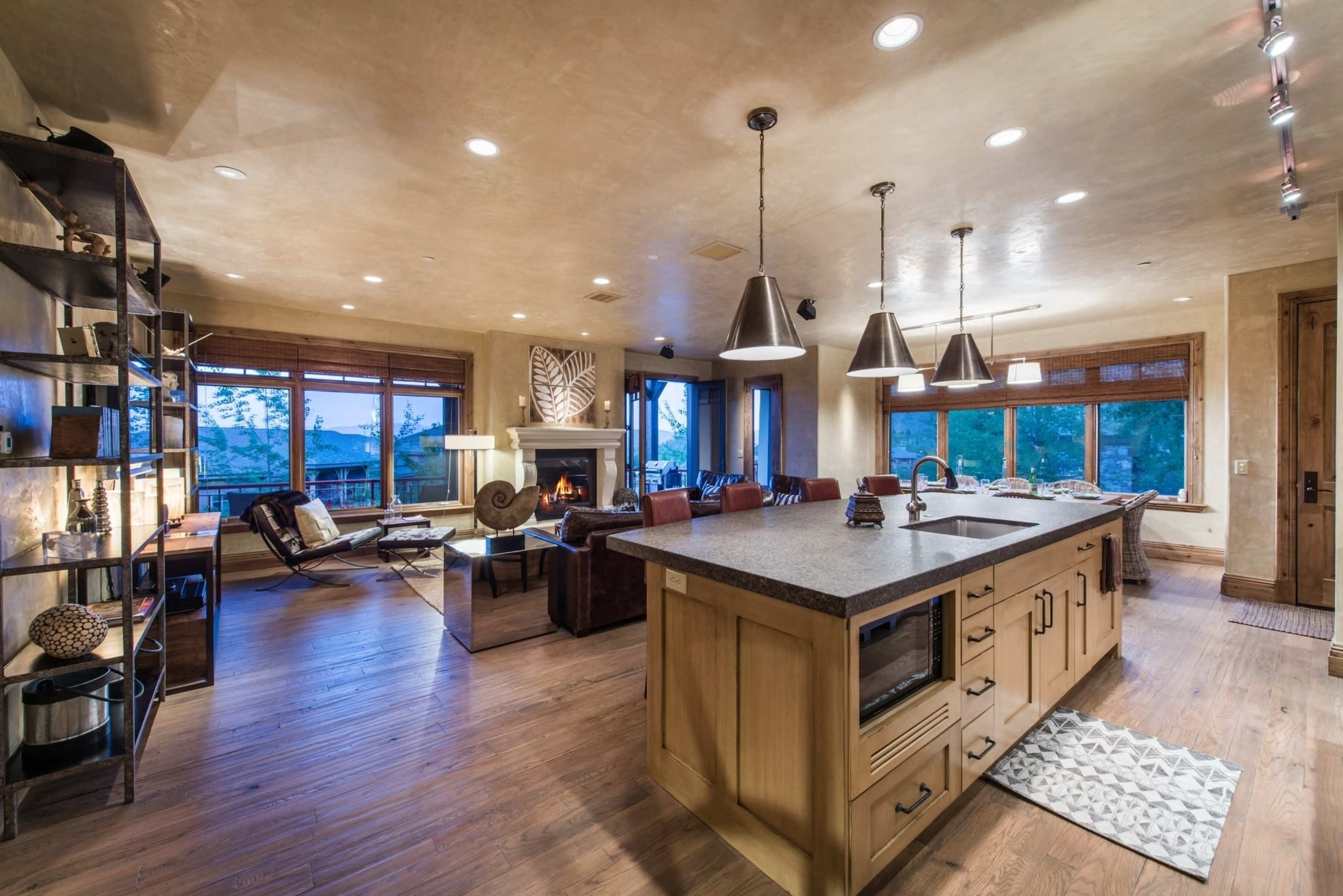 A modern open-concept living space featuring a kitchen with a central island, a dining area, and a cozy seating arrangement near a fireplace.