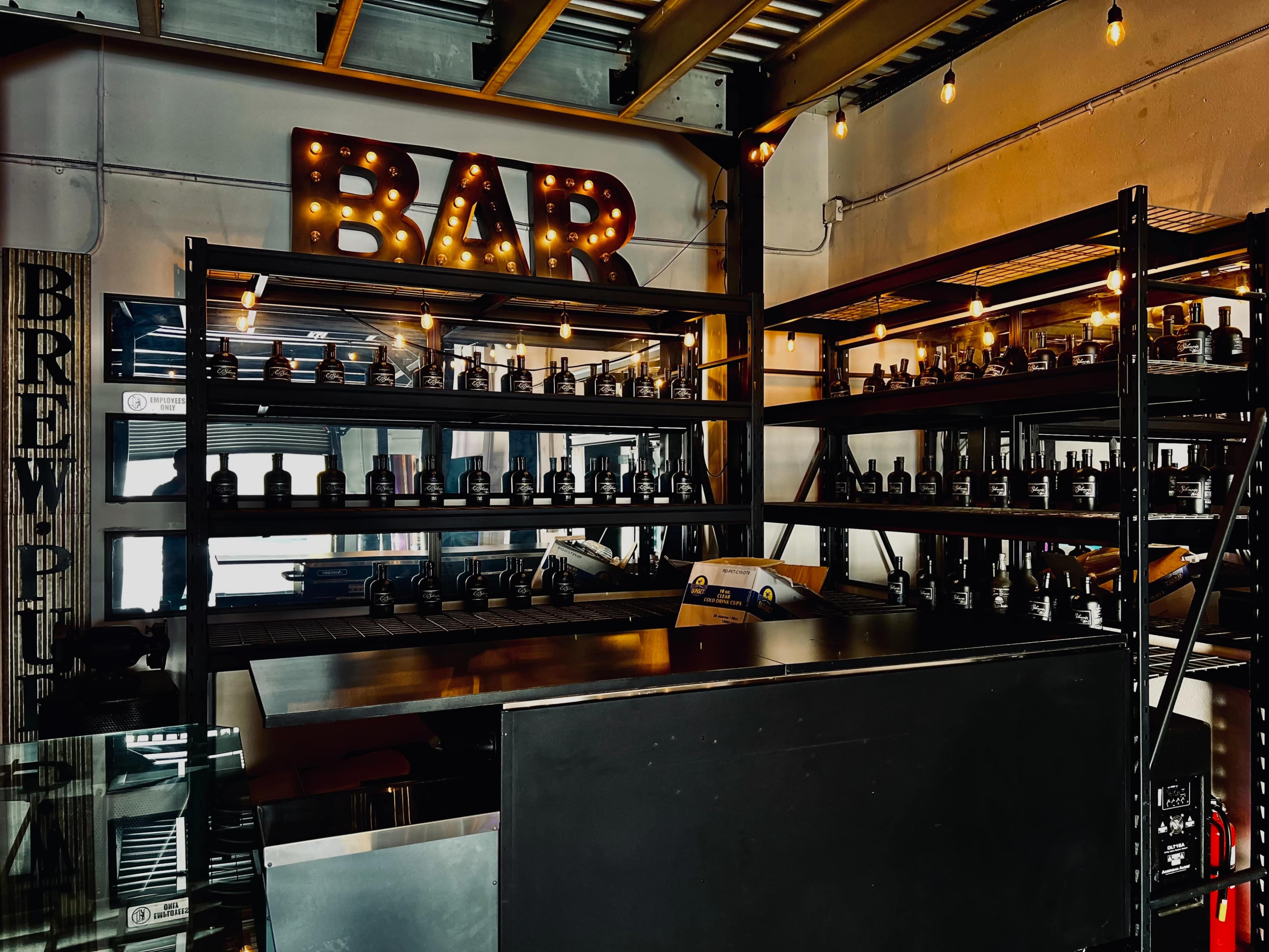 A bar area with illuminated signage and shelves lined with jars or bottles.