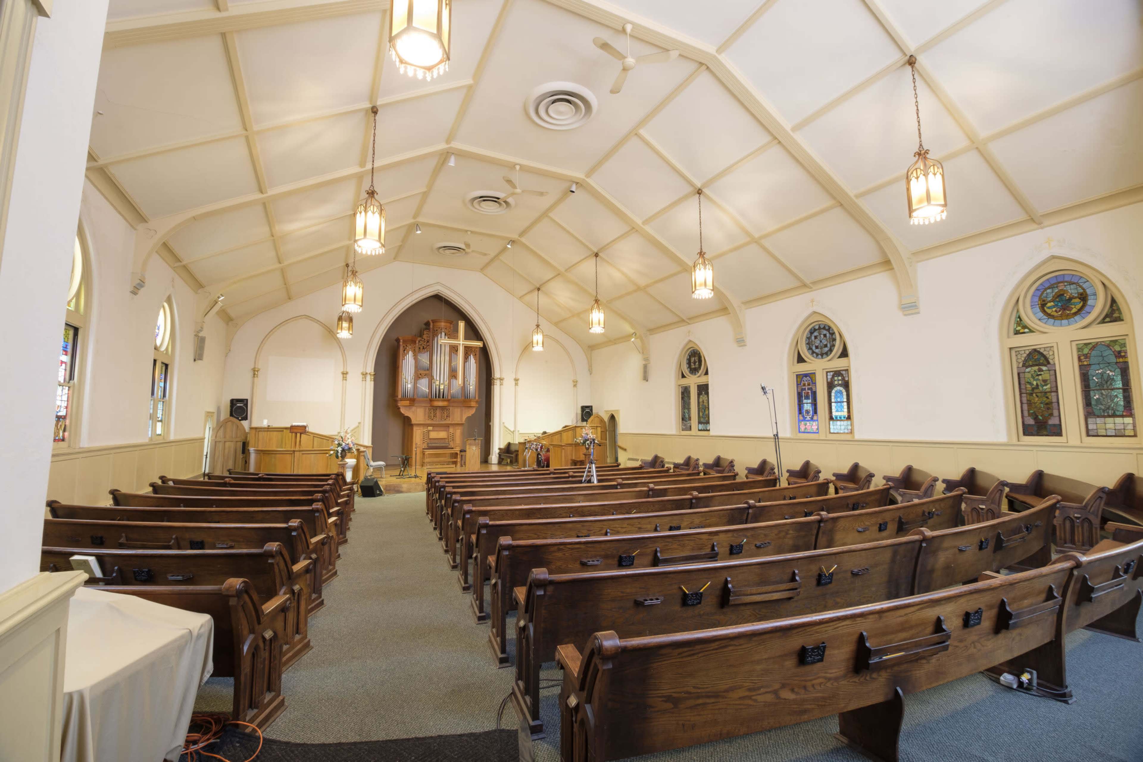 The interior of a church features wooden pews arranged in rows facing a central altar with a pipe organ in the background.