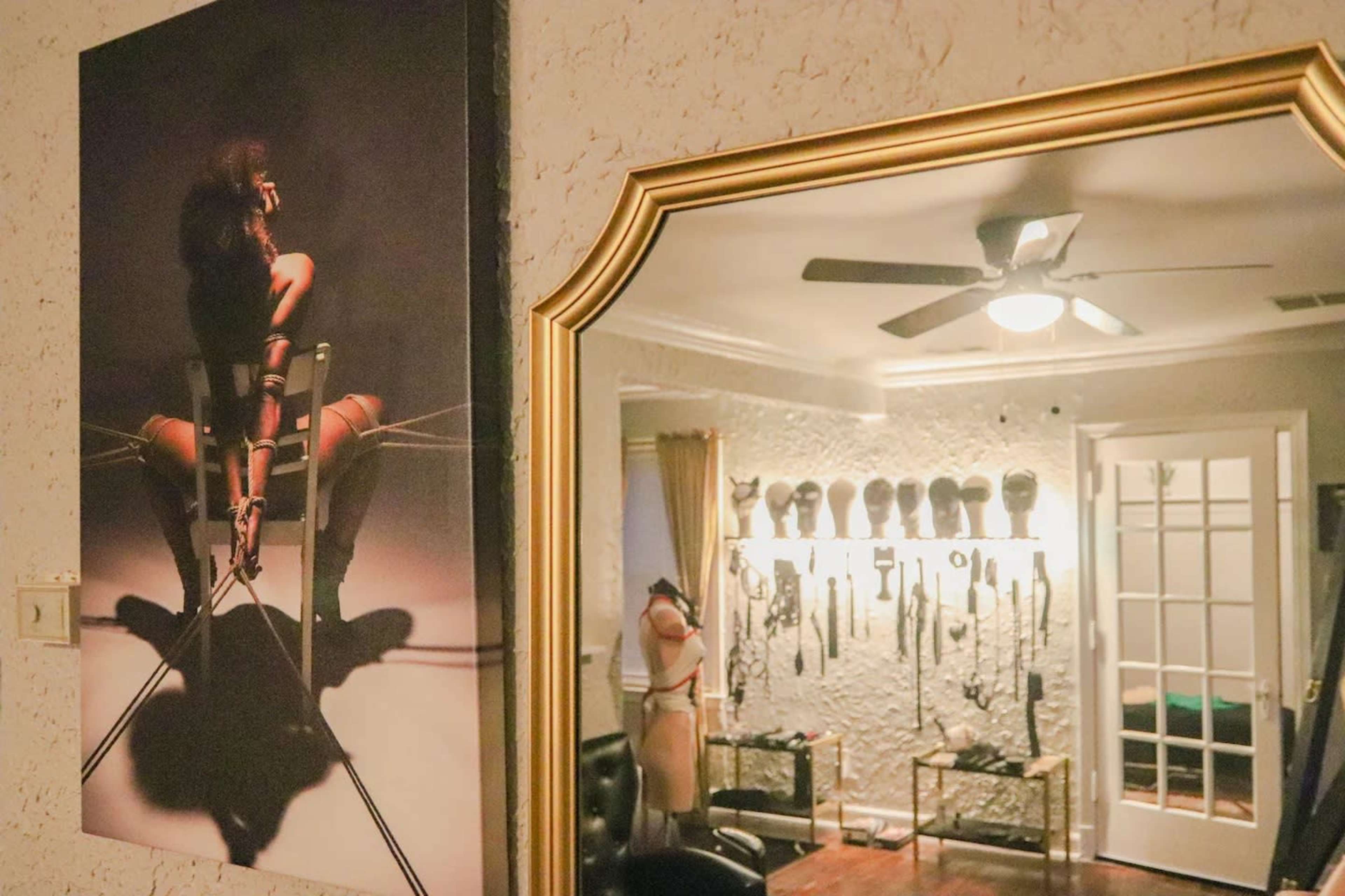 A room with a framed artwork on the wall, reflecting various items and figures displayed against a contrasting background.