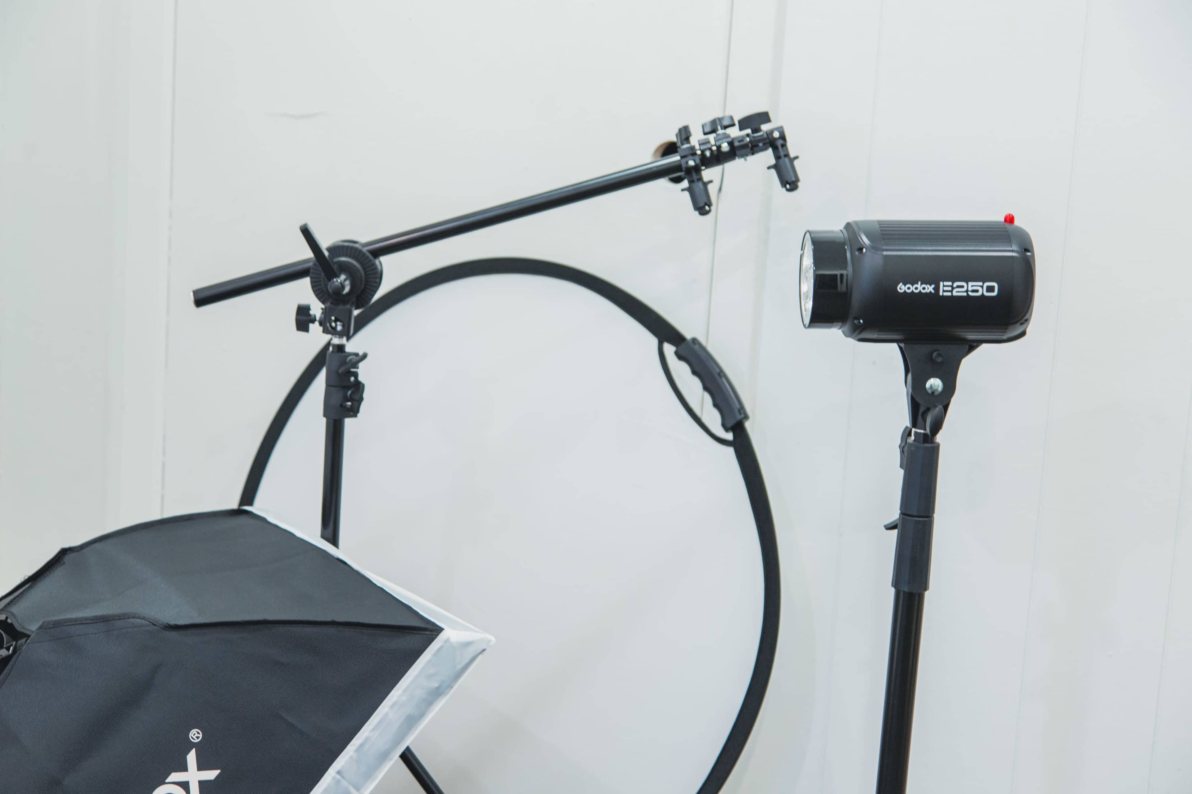 A Godox E250 studio light setup alongside a light stand and a circular reflector.