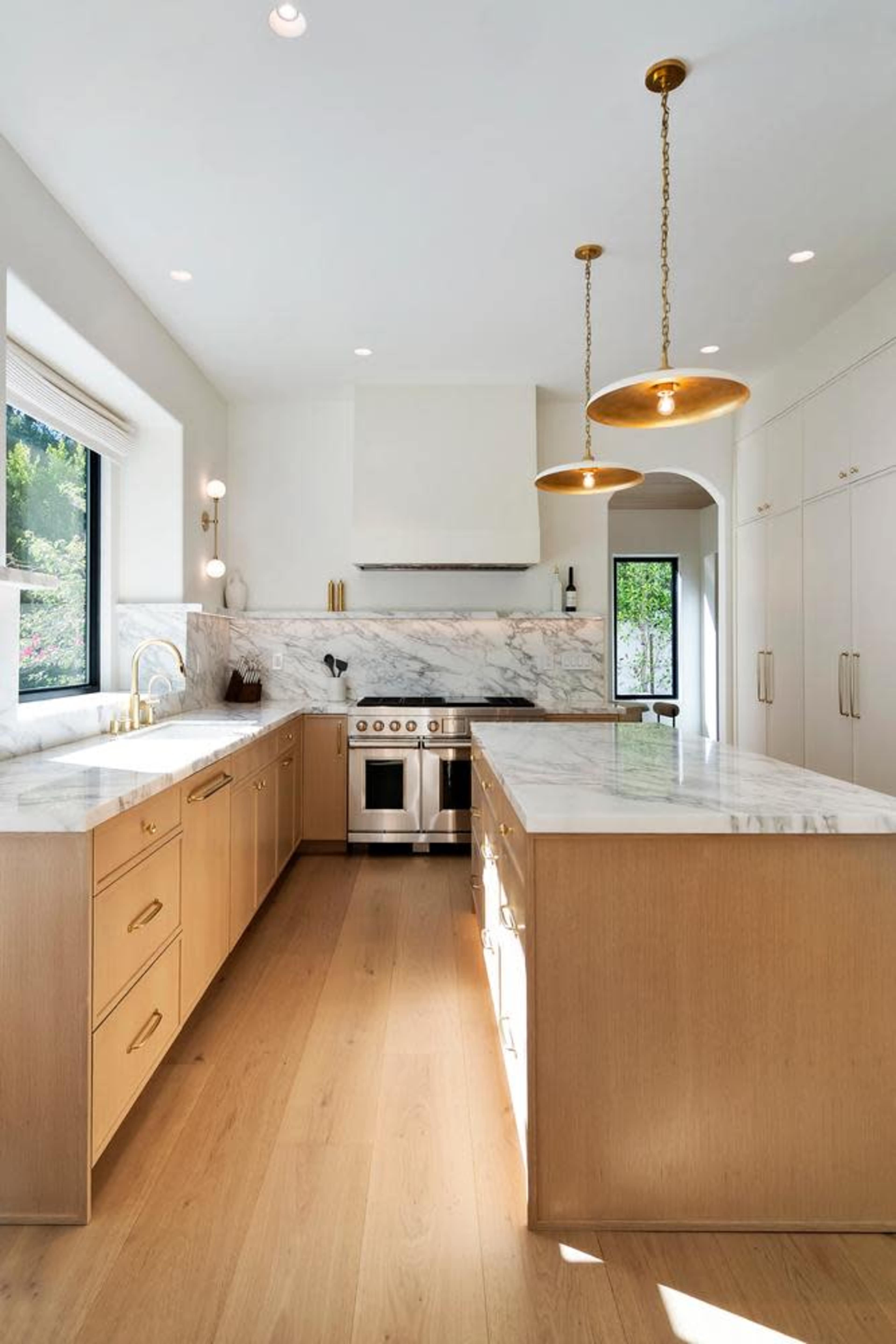 The kitchen features a spacious layout with marble countertops, wooden cabinetry, and modern pendant lighting.