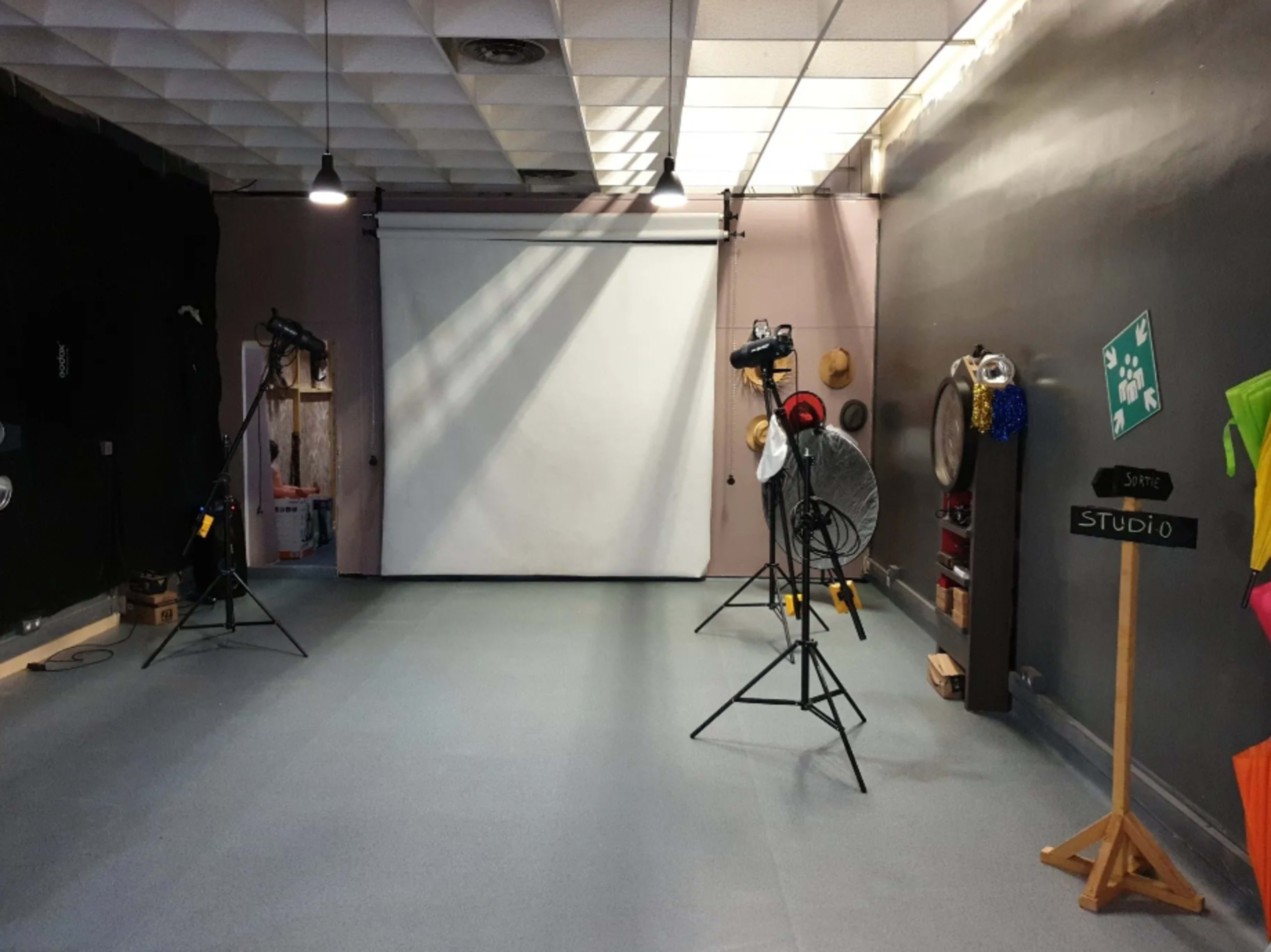 A photography studio with a backdrop, lighting equipment, and a chalkboard sign labeled "STUDIO."