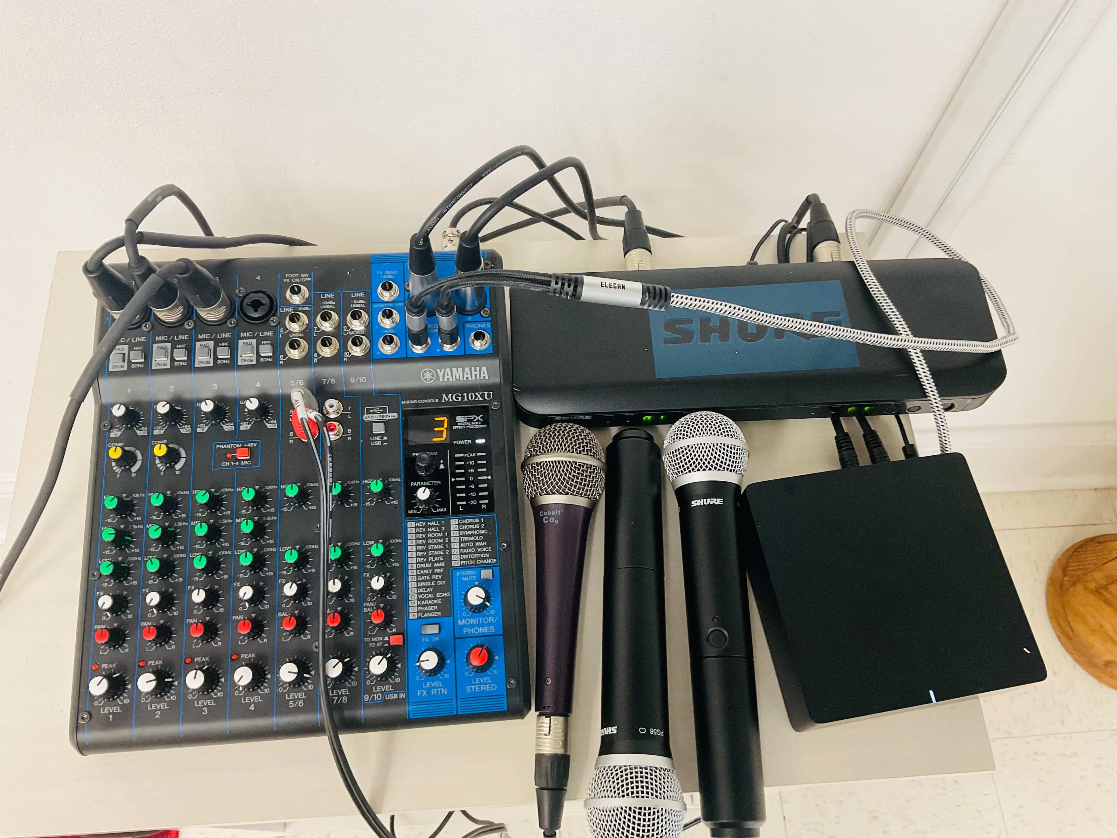 A Yamaha mixing console with multiple microphones and cables is set up on a table.