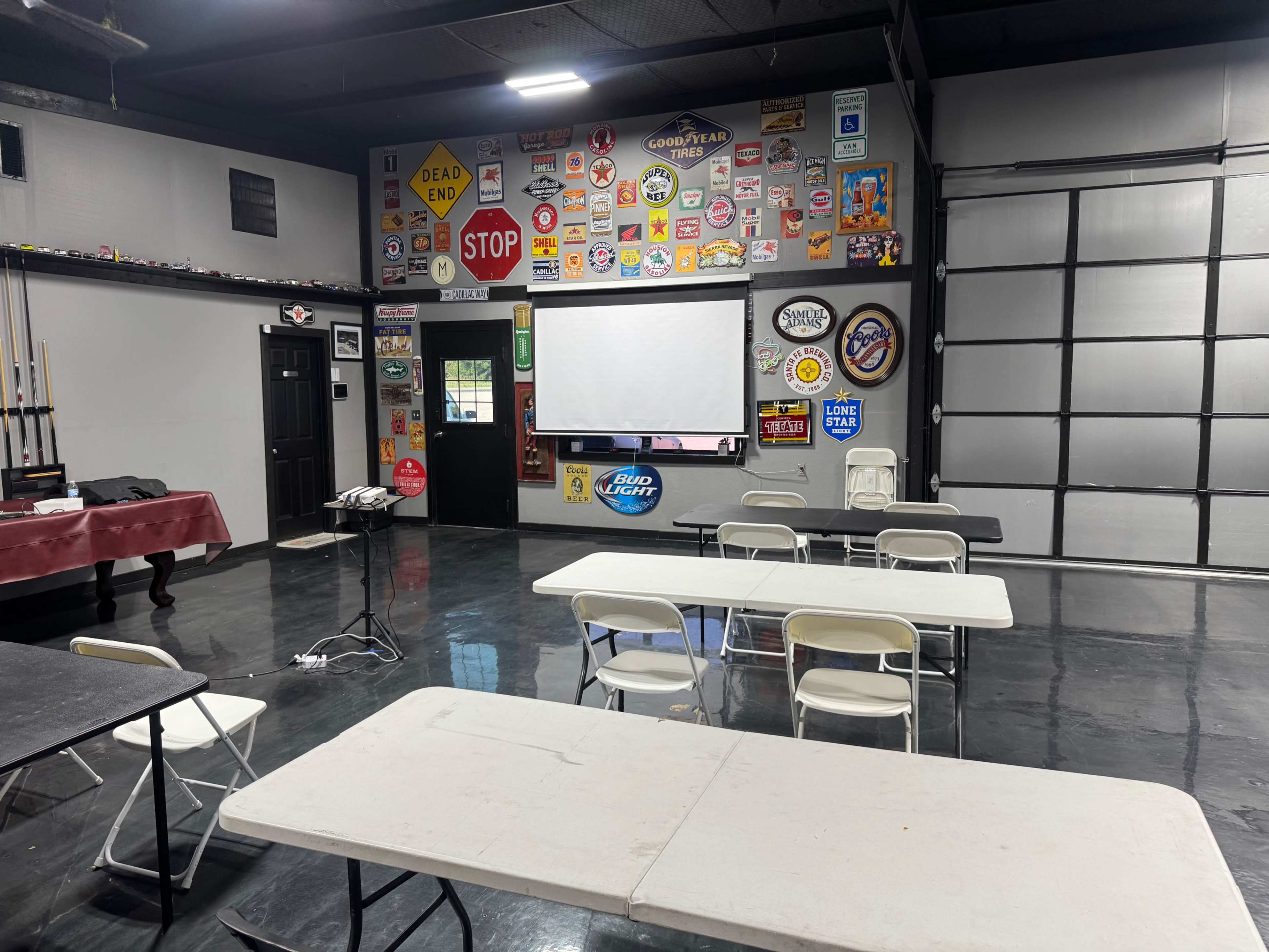 The image shows a room with several tables and chairs arranged for a meeting, decorated with various signs and memorabilia on the walls.