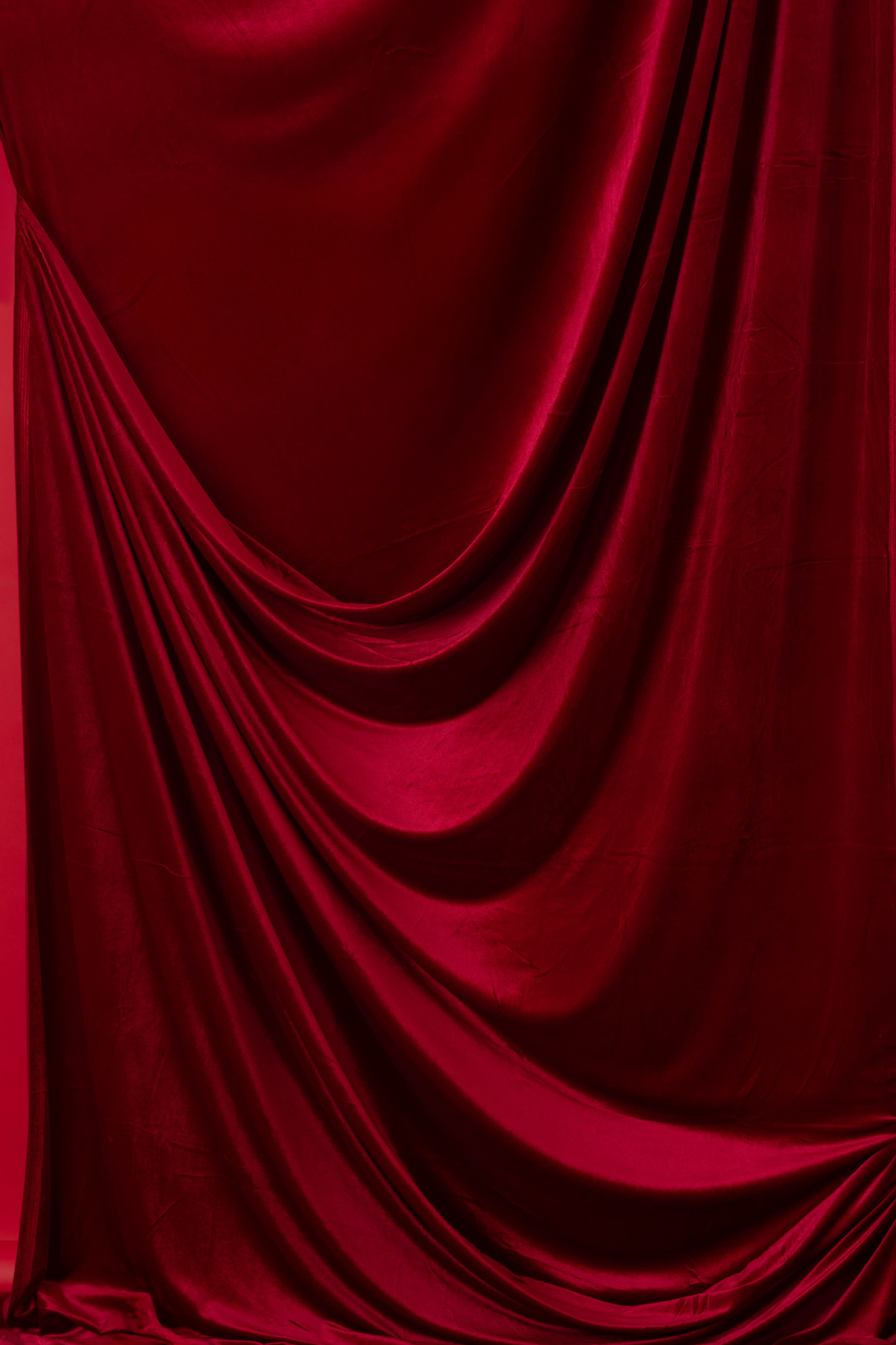 The image shows a rich red fabric draped in smooth folds and curves.