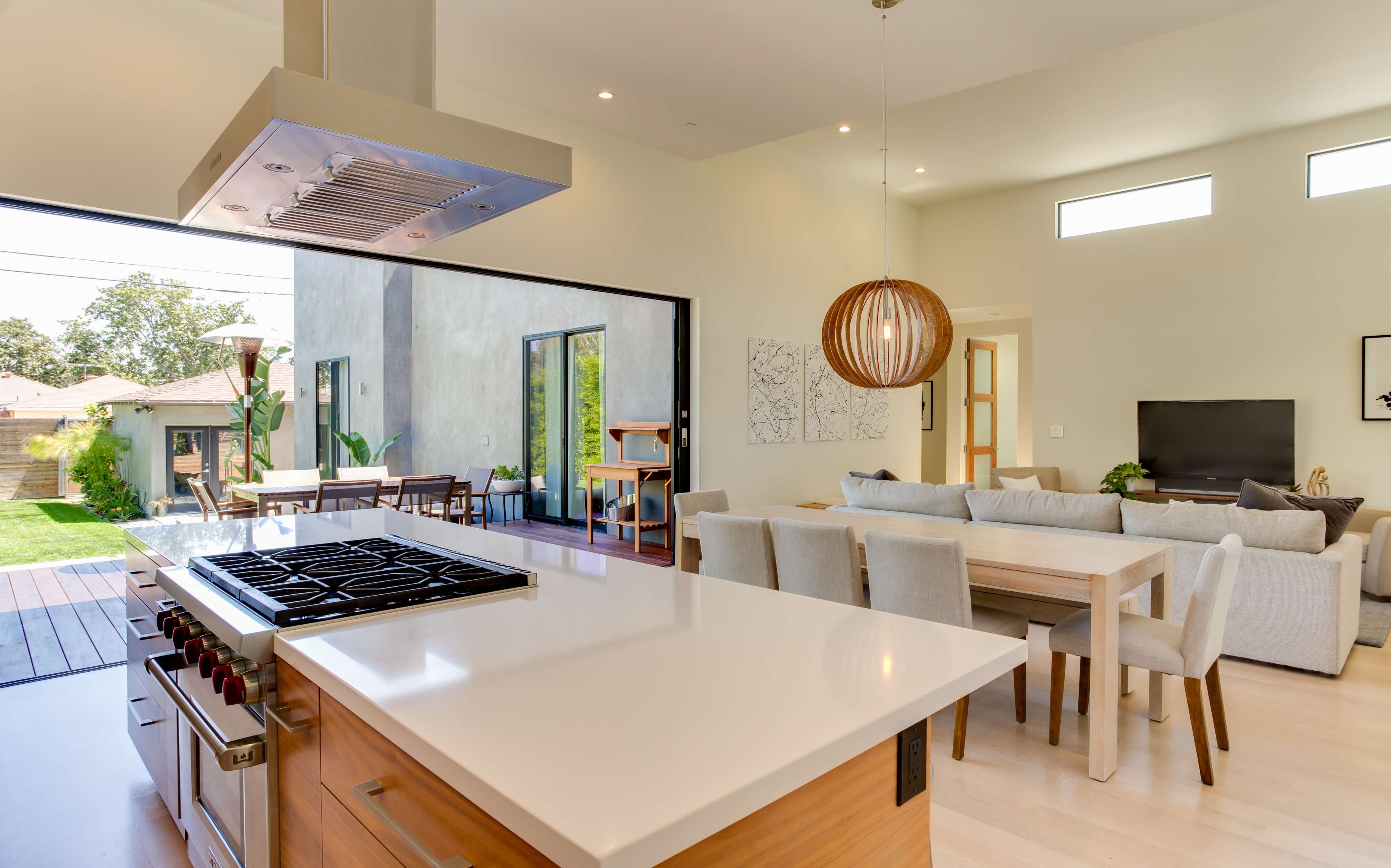 The open-concept kitchen features a sleek island with a gas stove, seamlessly connecting to a dining area and living space with large windows that invite natural light.