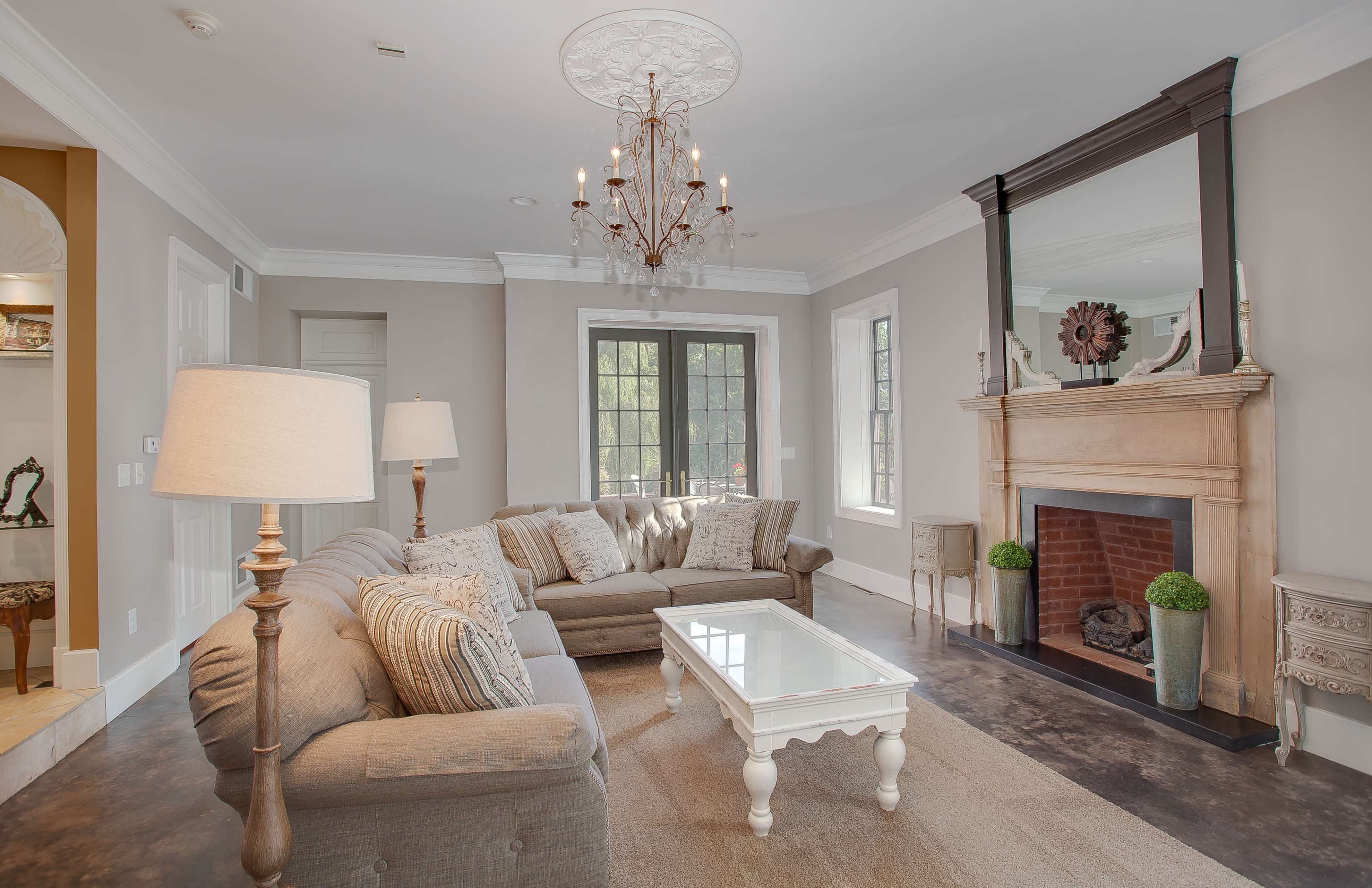 A living room with a chandelier, a fireplace, a coffee table, and two sofas arranged around a central area.