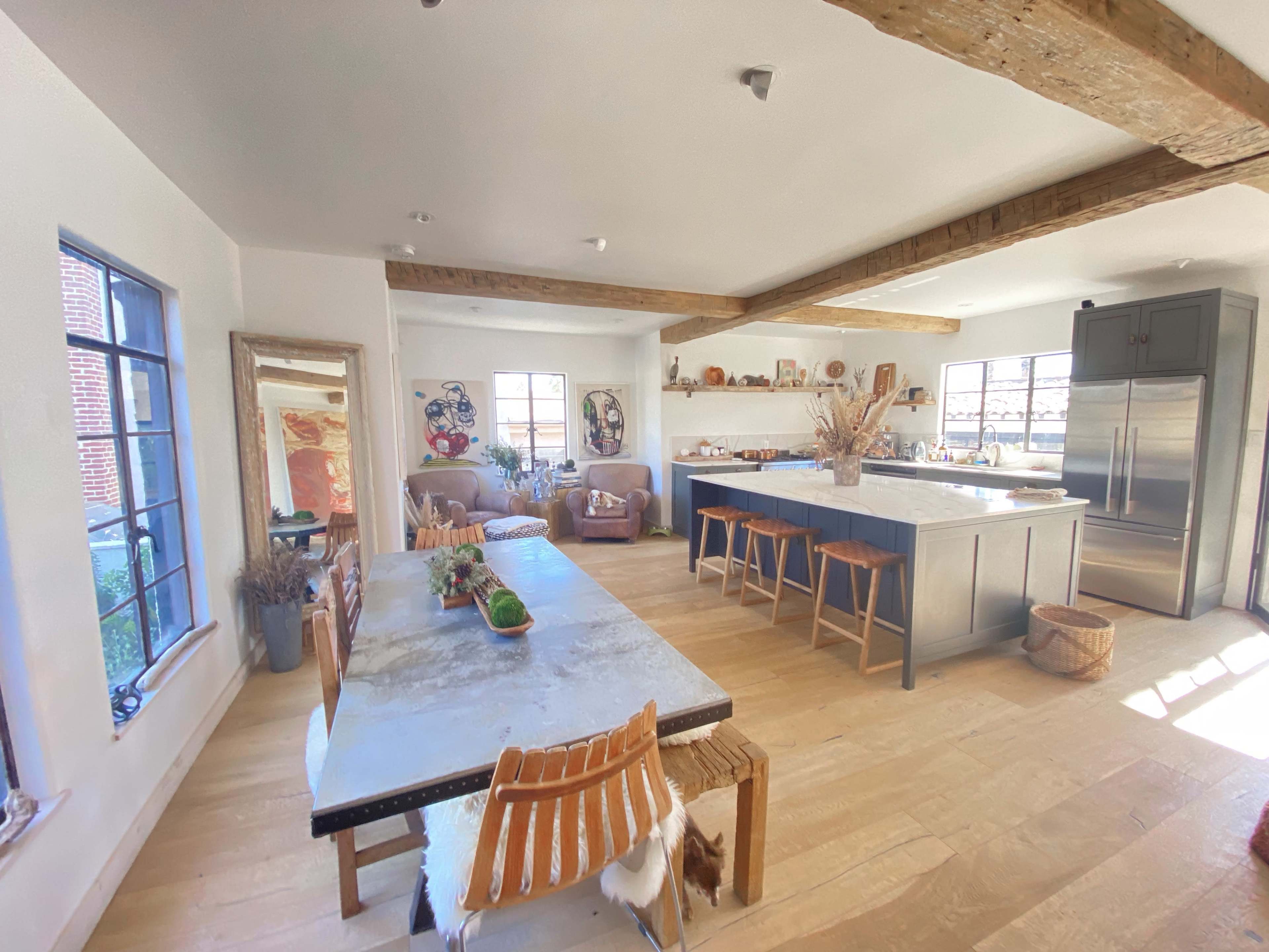 A spacious kitchen with a large dining table, modern appliances, and wooden beams on the ceiling.
