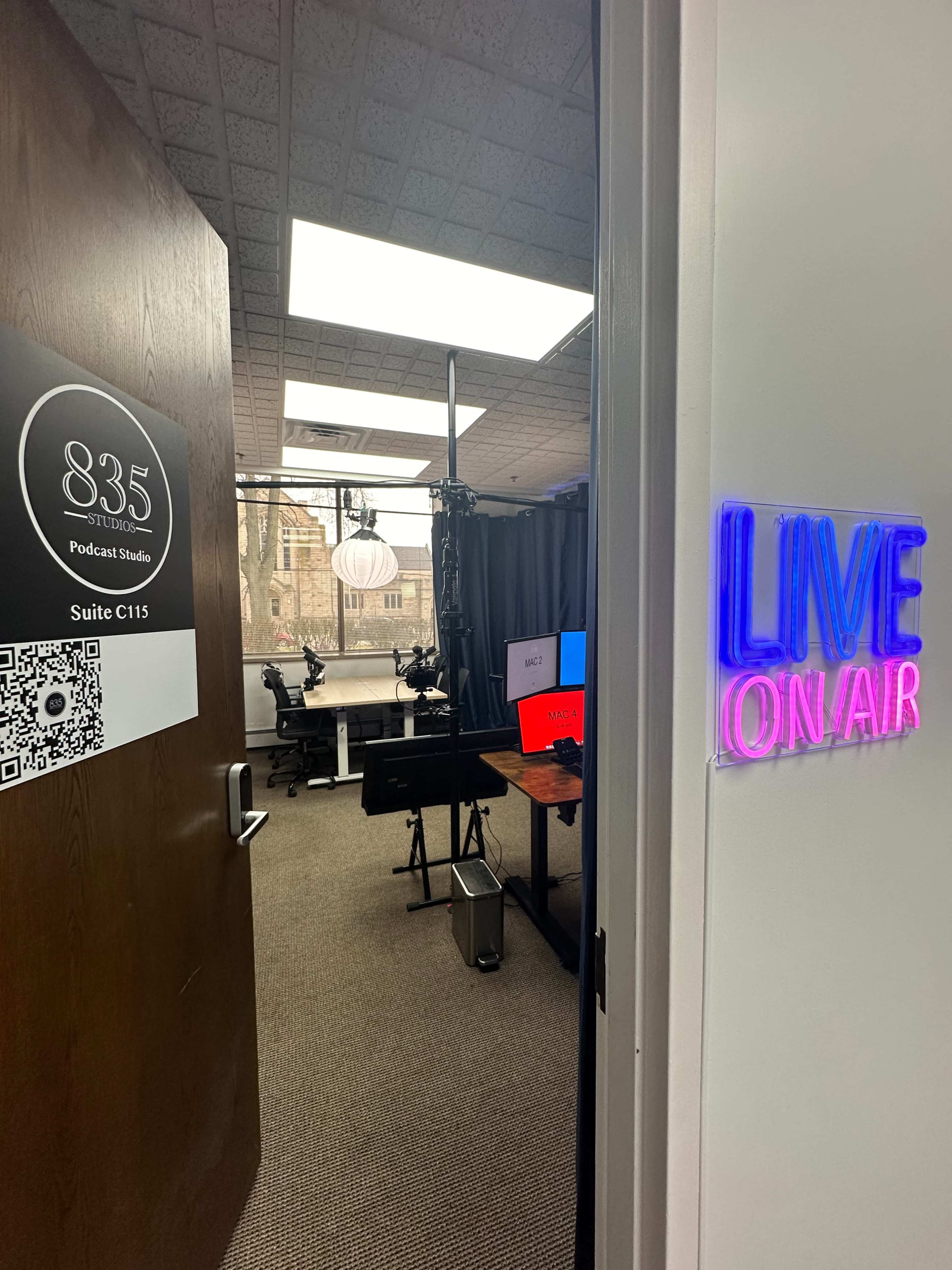 The entrance to a podcast studio with a sign indicating "835 Podcast Studio" and a glowing "LIVE ON AIR" sign alongside the door.