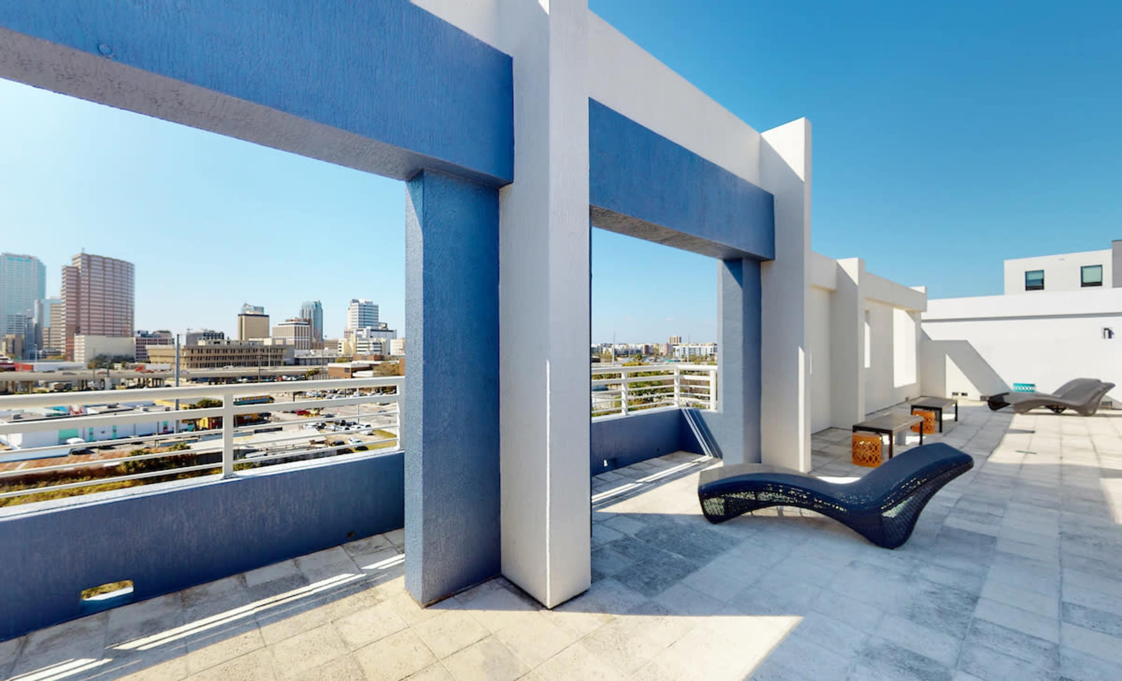 A rooftop terrace with modern architectural features and a skyline view of a city.