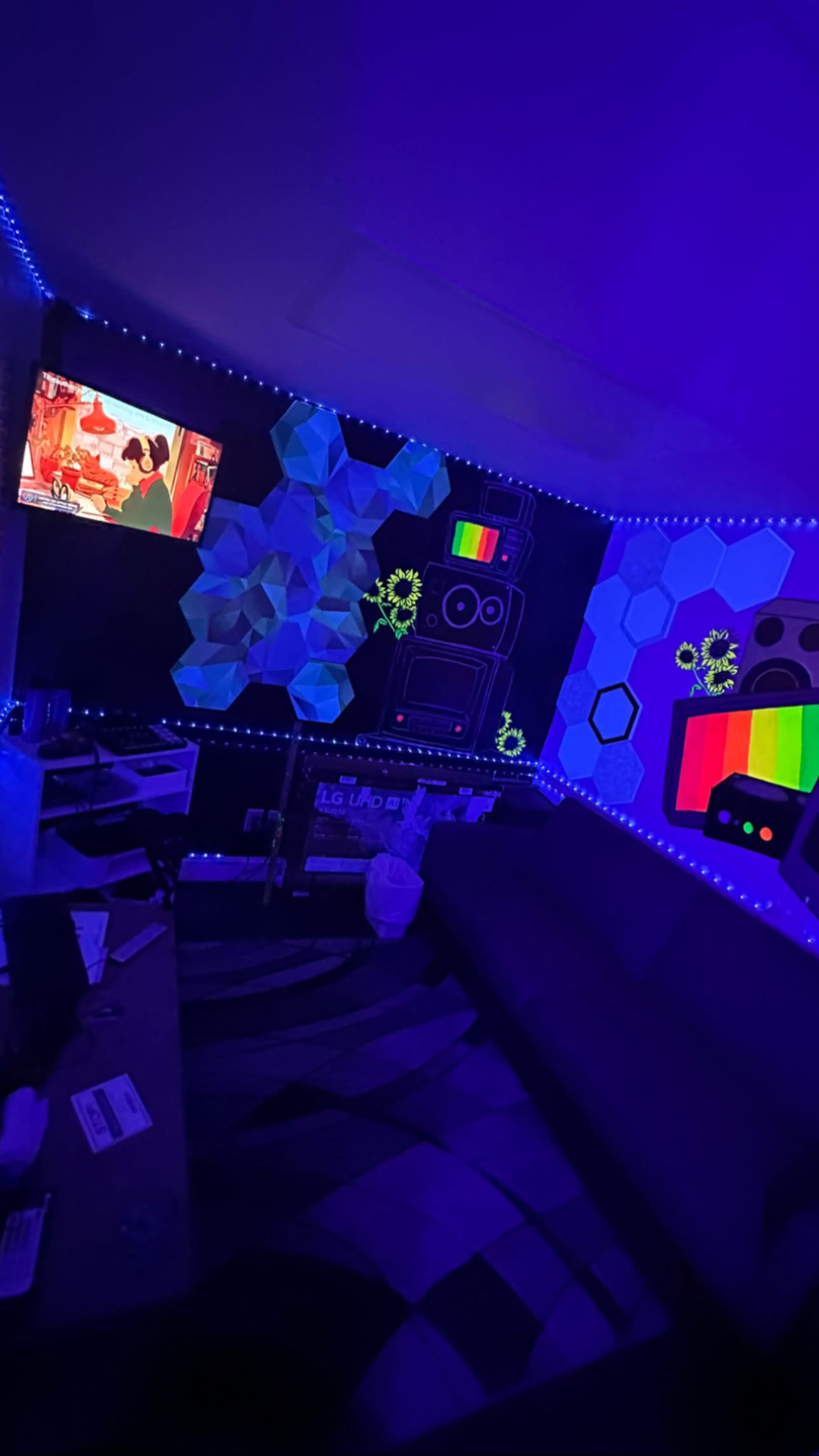 The room features a dark setting illuminated by purple lights, with a television showing a colorful animation and walls decorated with geometric designs and neon accents.